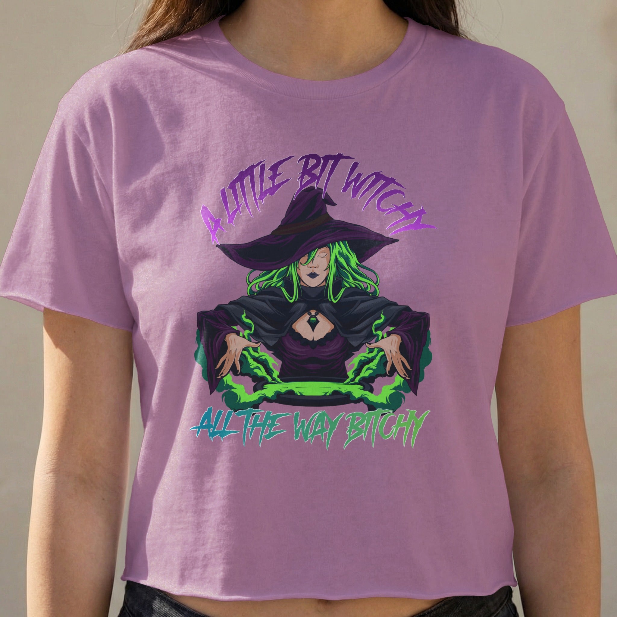 Witch with green hair and a hat on a purple t-shirt saying "A little bit witchy, all the way bitchy".