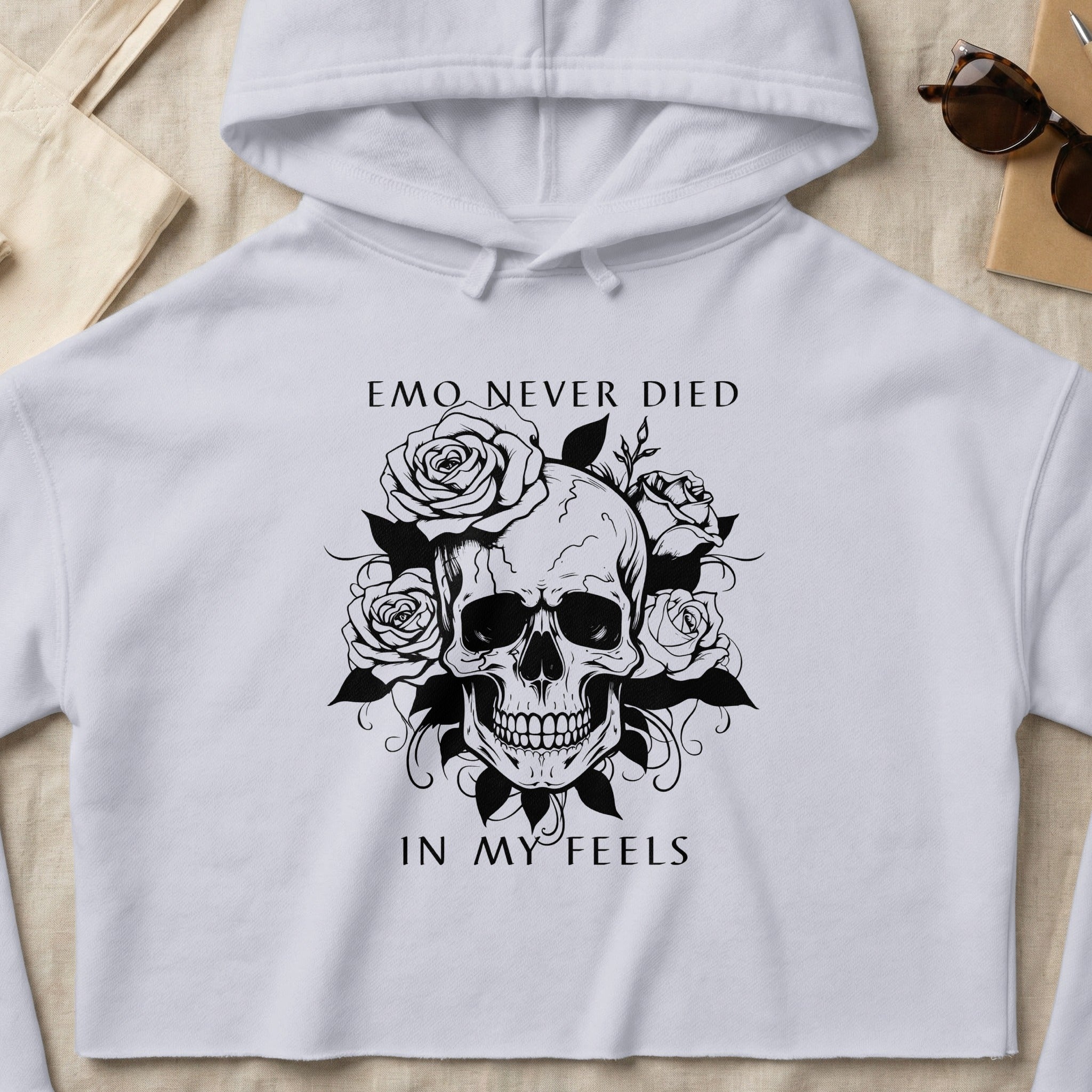 White cropped hoodie with skull and roses graphic, text "EMO NEVER DIED IN MY FEELS".