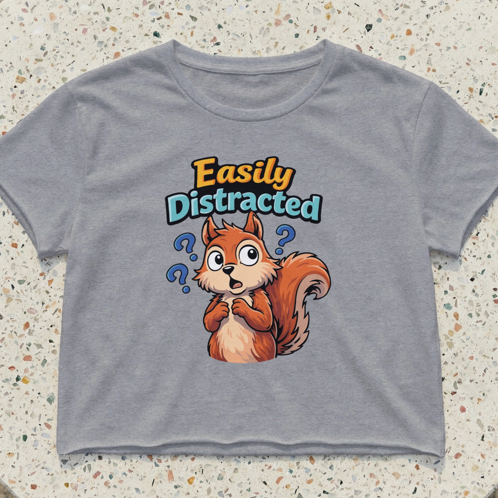 Grey cropped t-shirt with a cartoon squirrel and "Easily Distracted" text.