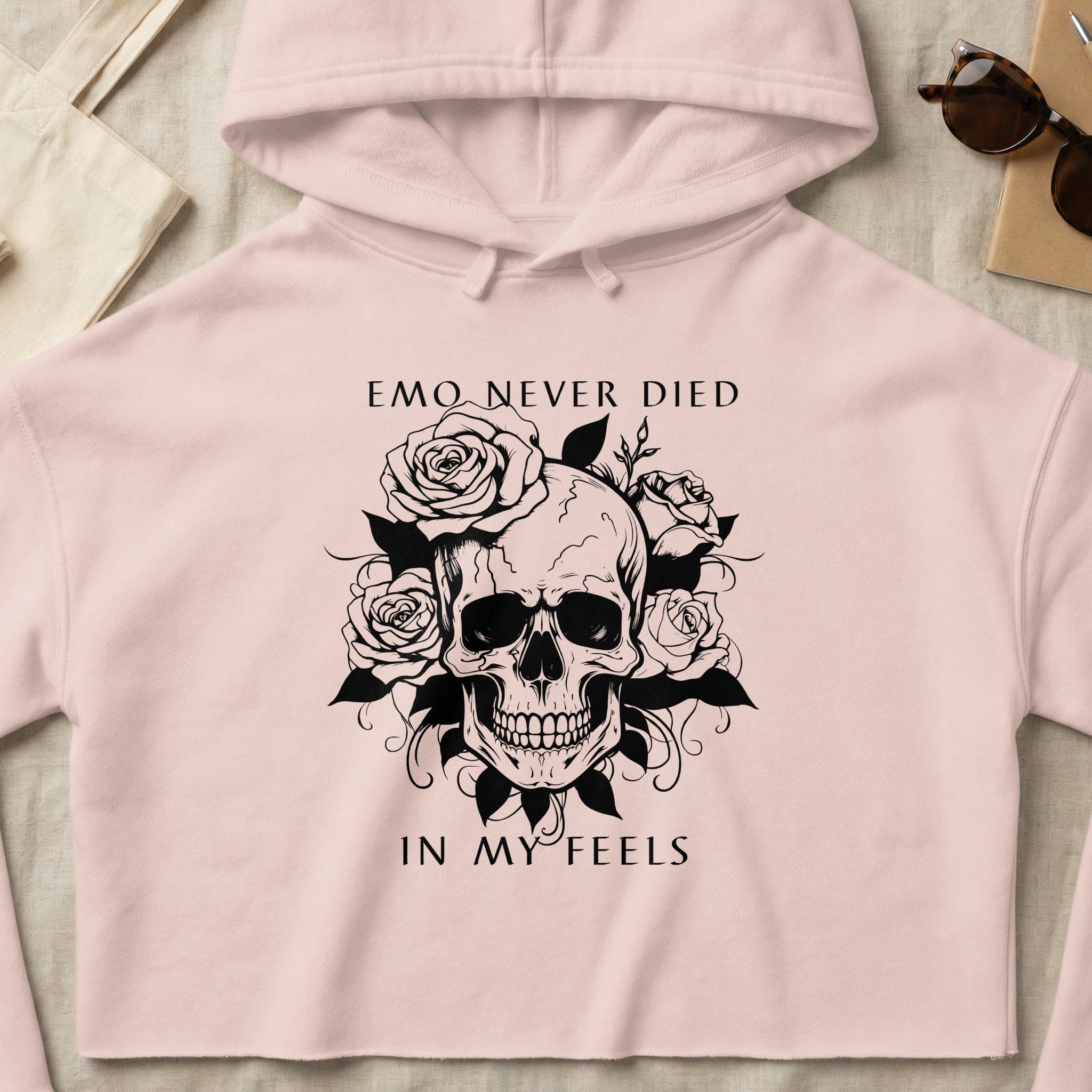 Pink cropped hoodie with black skull and rose graphic and text "EMO NEVER DIED IN MY FEELS".