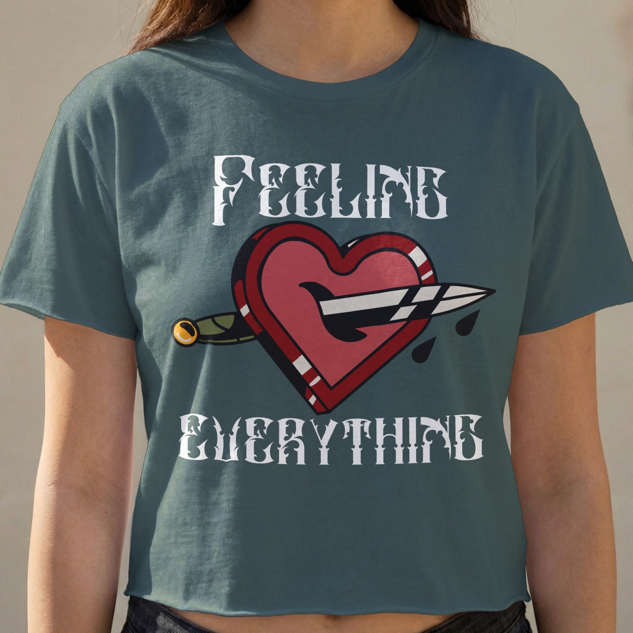 Dark t-shirt with a heart pierced by a knife and the text "FEELING EVERYTHING".