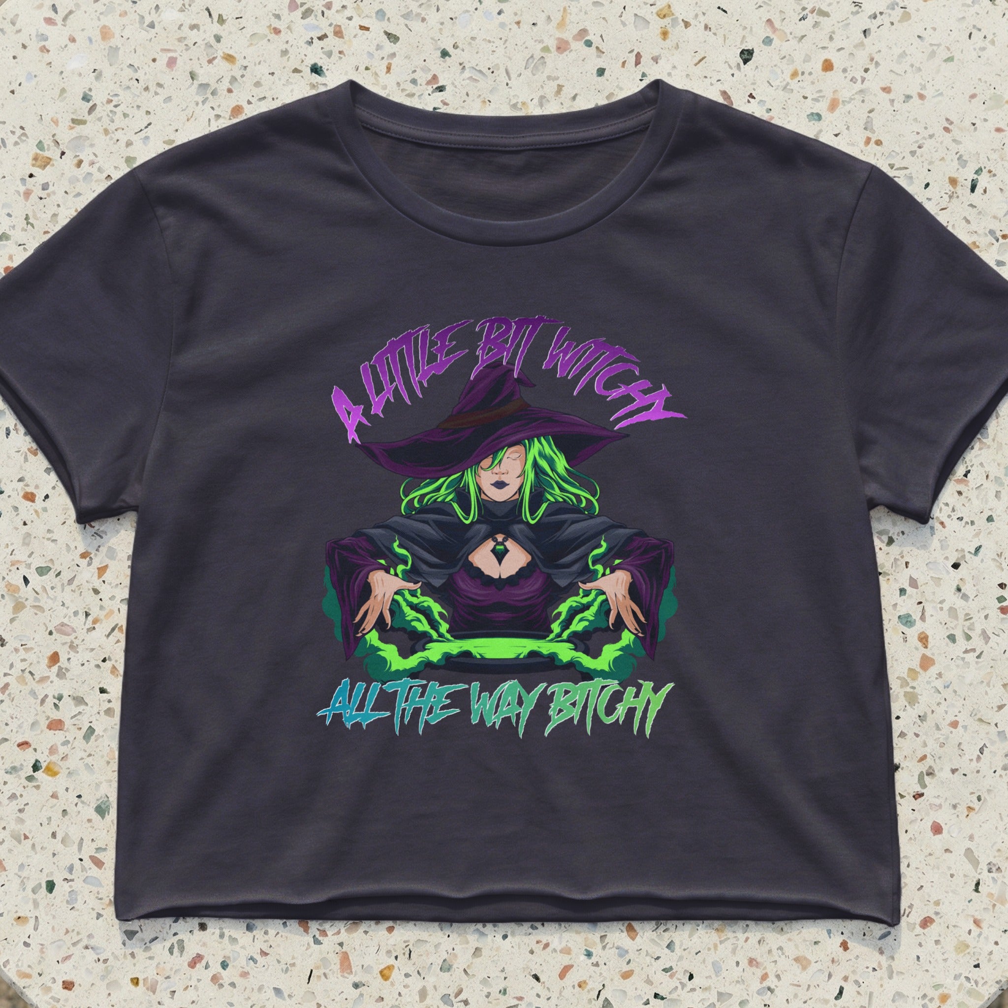 Dark crop top with a witch graphic and the text "A little bit witchy all the way bitchy."