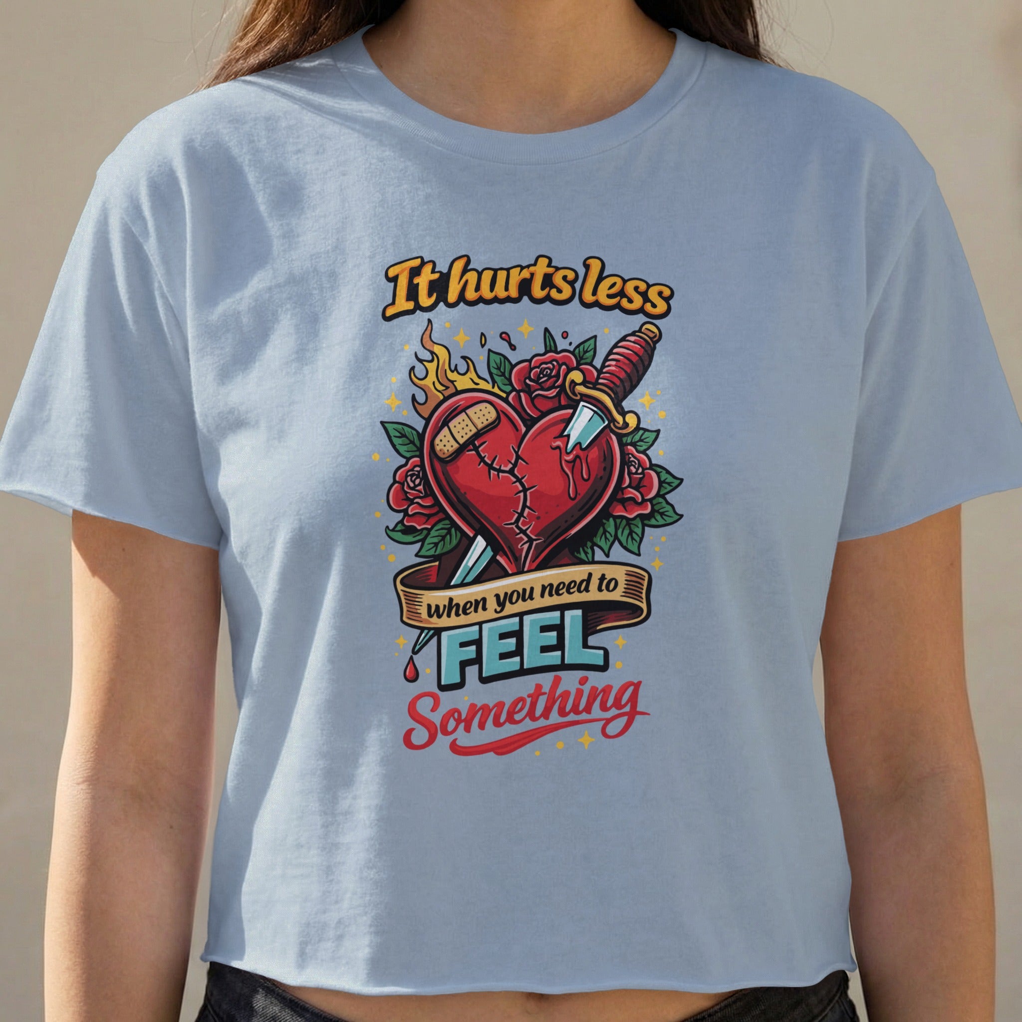 Light blue t-shirt with a graphic of a broken heart, knife, and text.