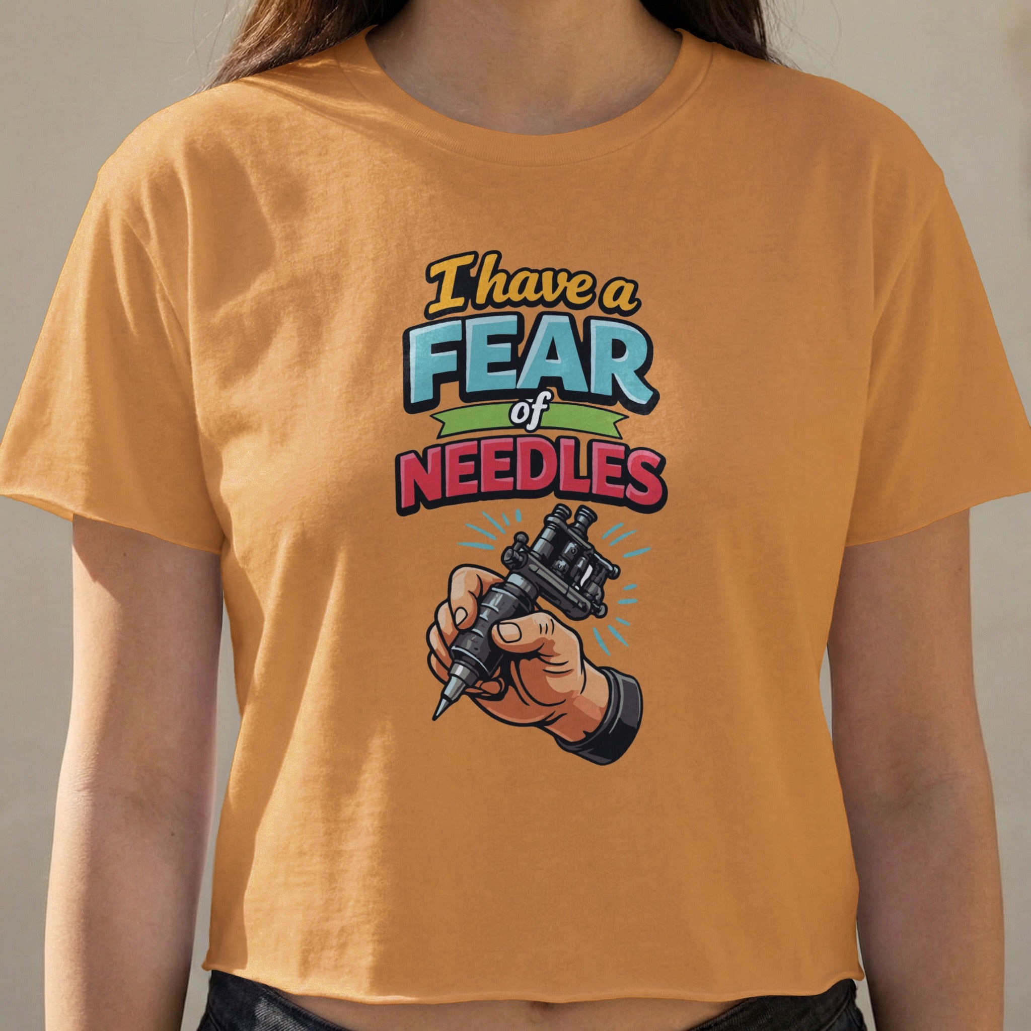 Orange t-shirt with "I have a fear of needles" text and tattoo gun graphic.