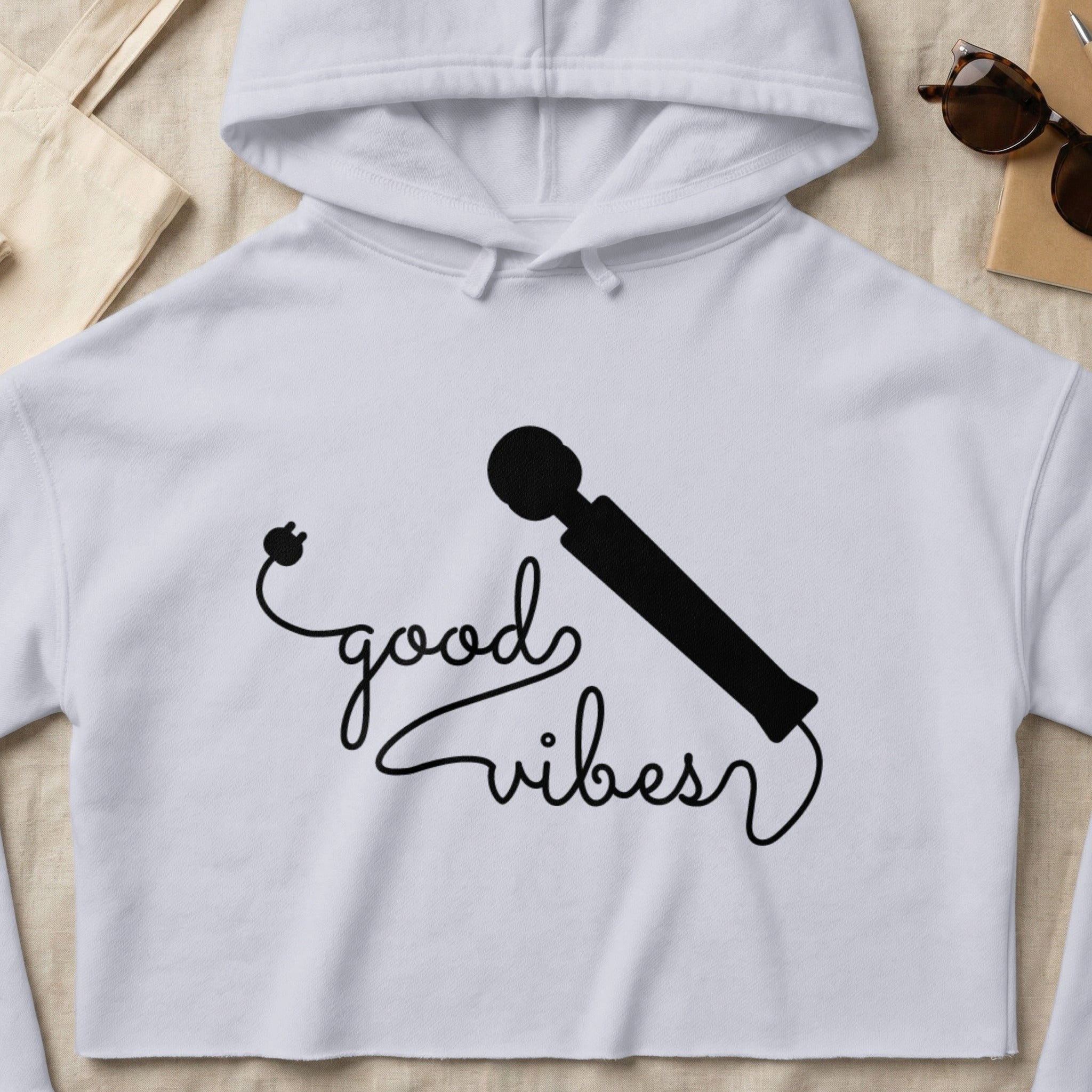 White cropped hoodie with "good vibes" graphic and a black illustration of a wand vibrator.