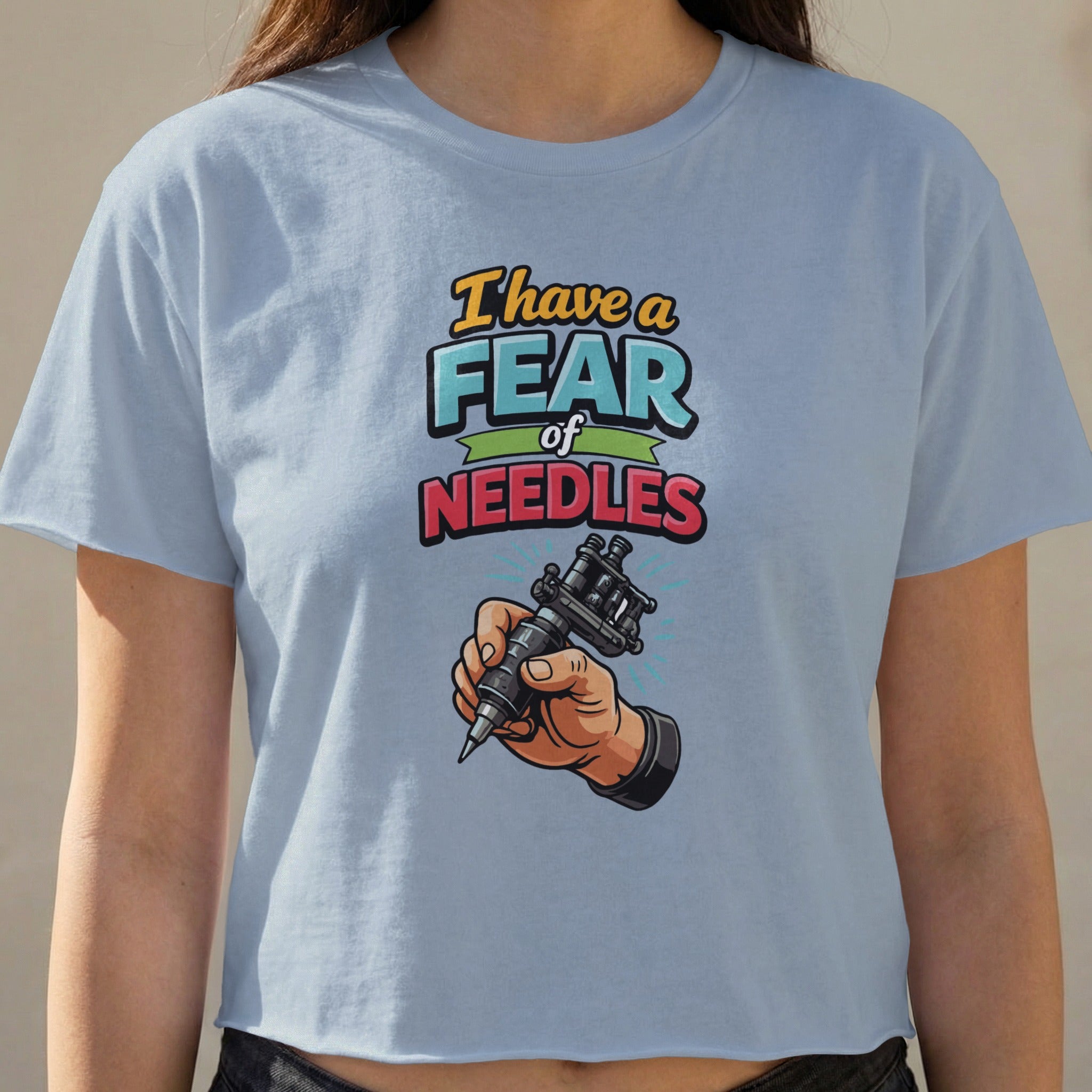 Light blue cropped t-shirt with "I have a fear of NEEDLES" text and a tattoo gun.
