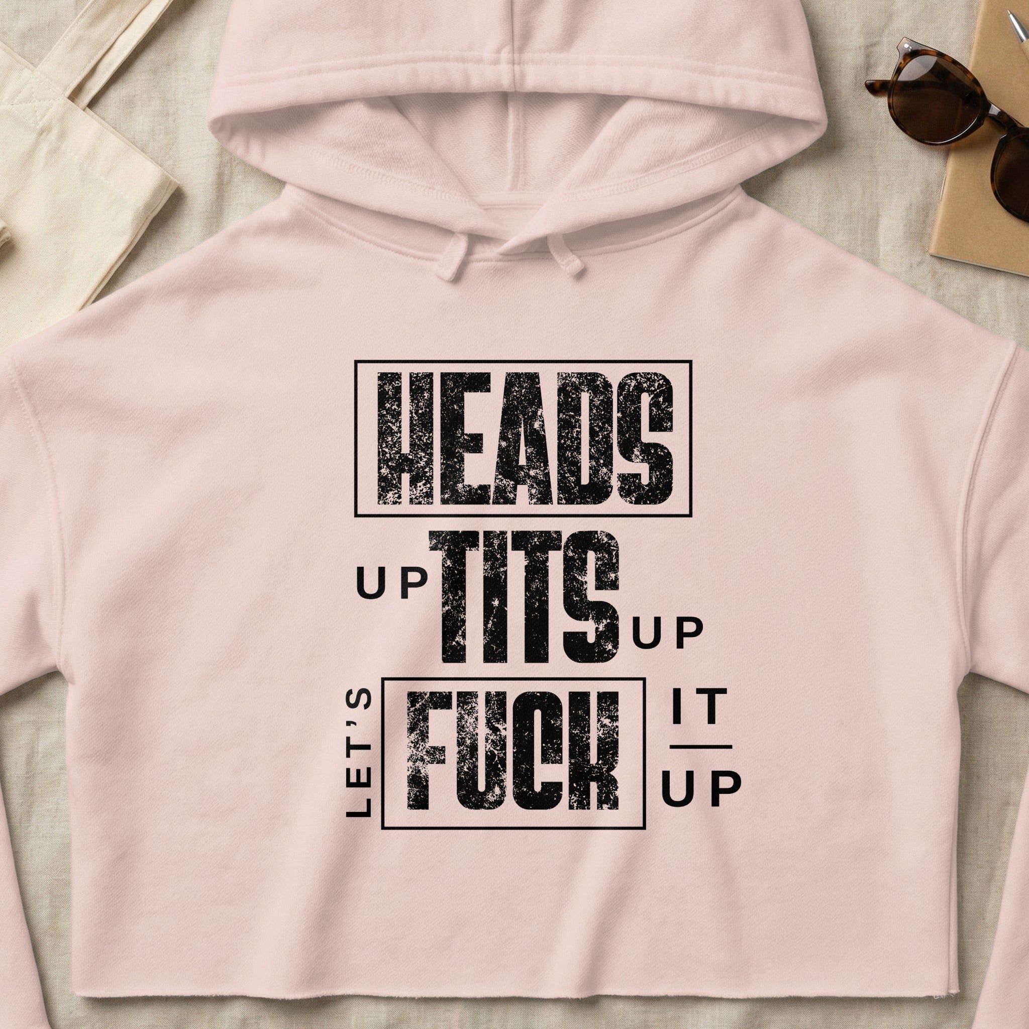Pink cropped hoodie with "HEADS UP TITS UP LET'S FUCK IT UP" graphic text.
