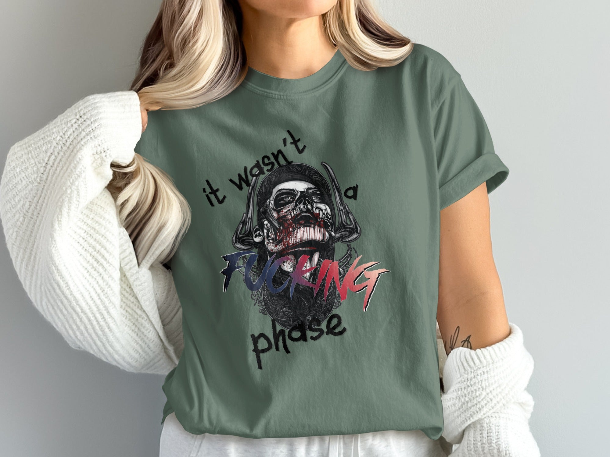 Green t-shirt with graphic of skull wearing headphones and text "it wasn't a fucking phase".