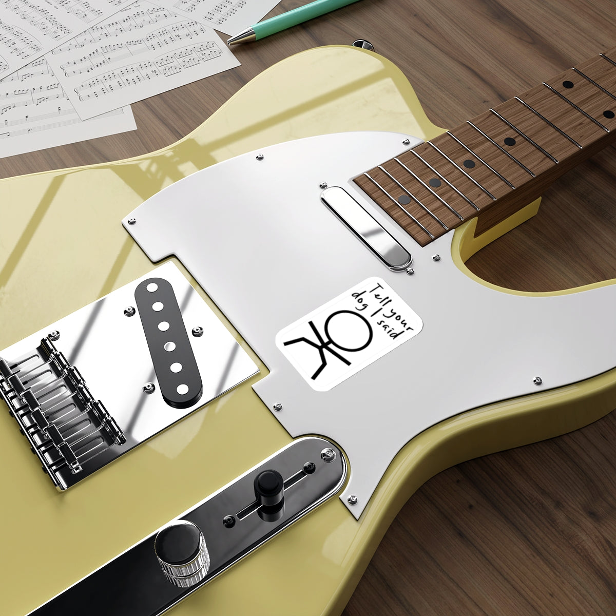 Yellow electric guitar with "Tell your dog said" sticker and sheet music.