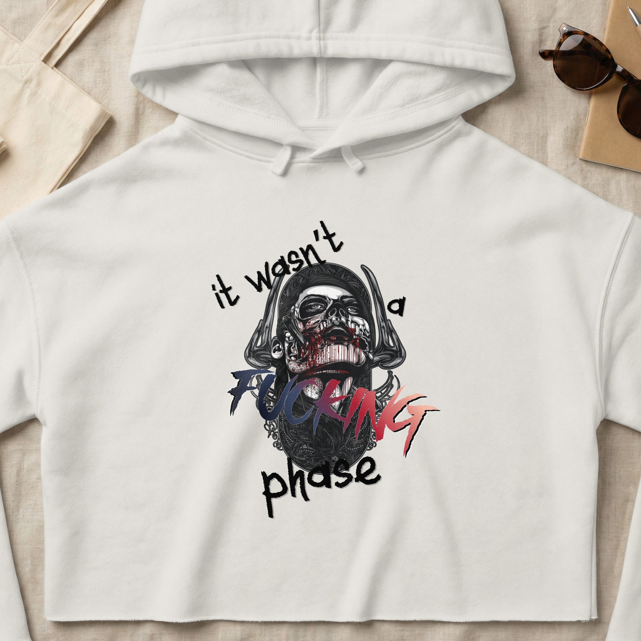 White cropped hoodie with "it wasn't a fucking phase" graphic.