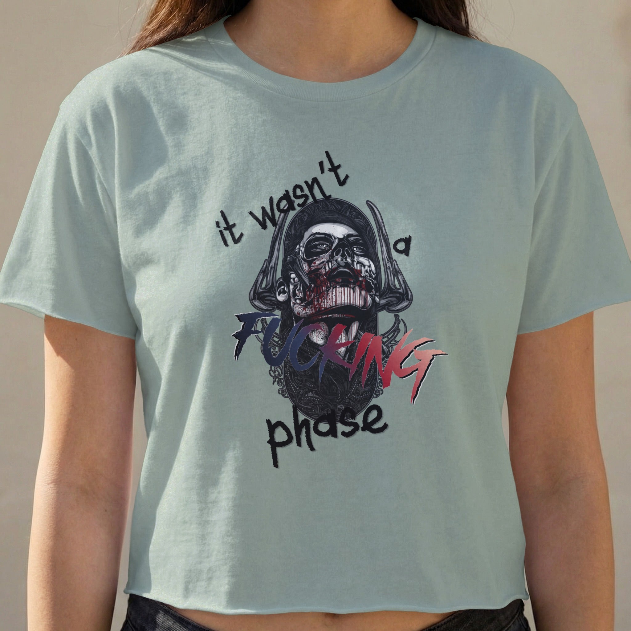 Light blue cropped t-shirt with skull graphic and text "it wasn't a fucking phase".