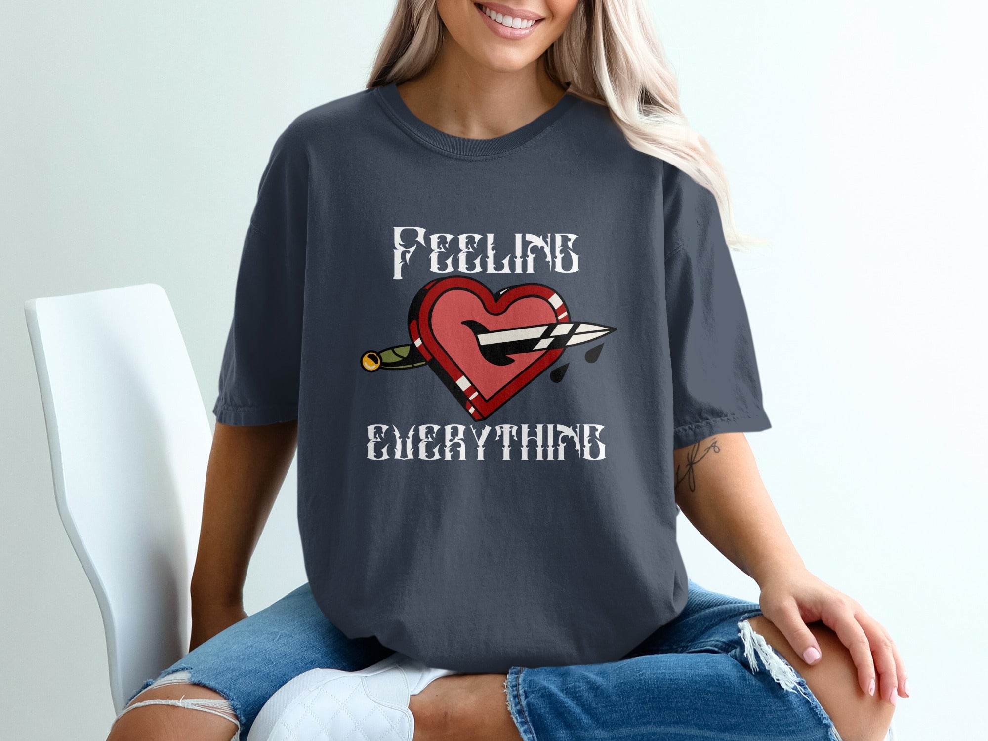 Dark gray t-shirt with "Feeling Everything" text and a heart pierced by a knife.