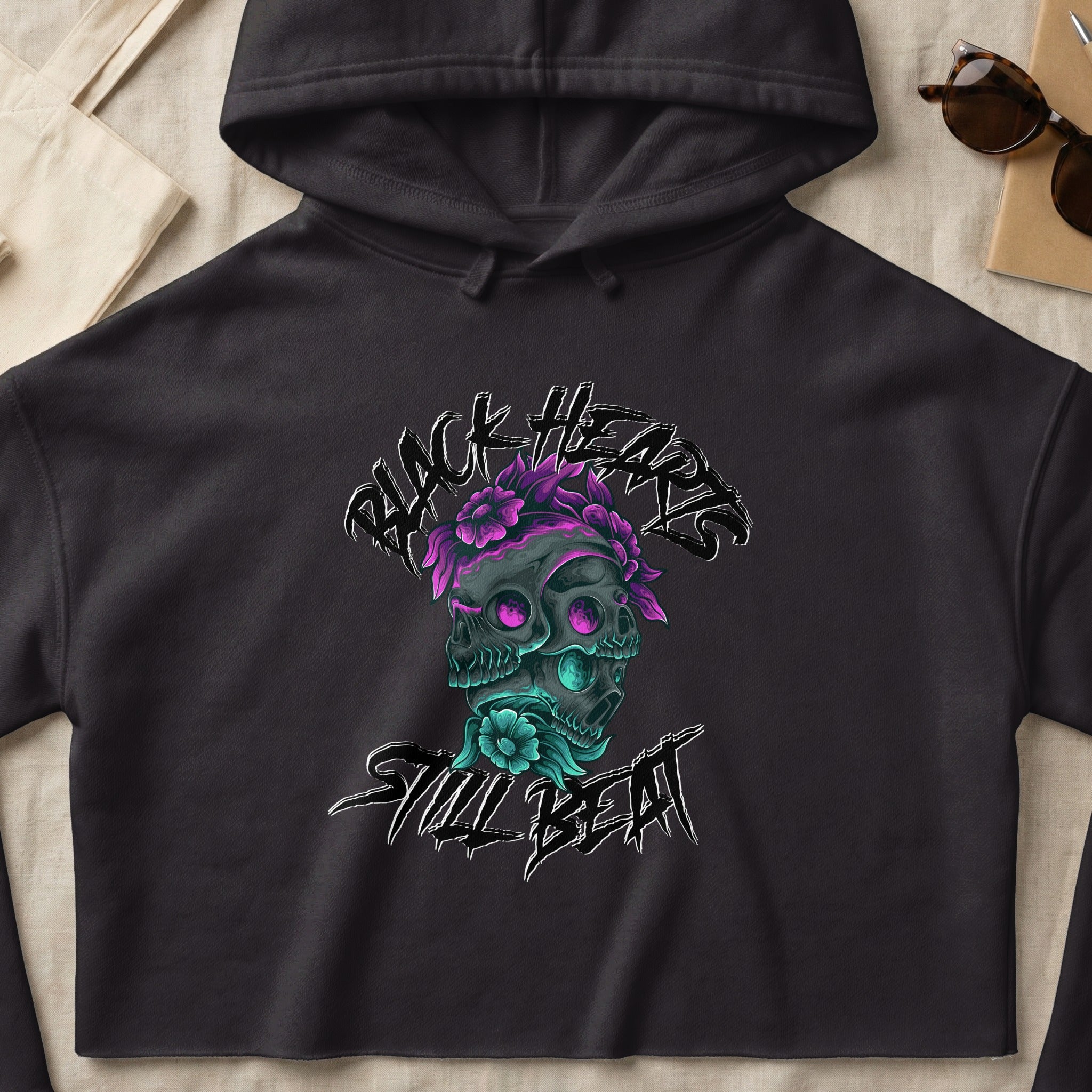 Black Hearts Still Beat text with skull and flowers graphic on a gray hoodie.