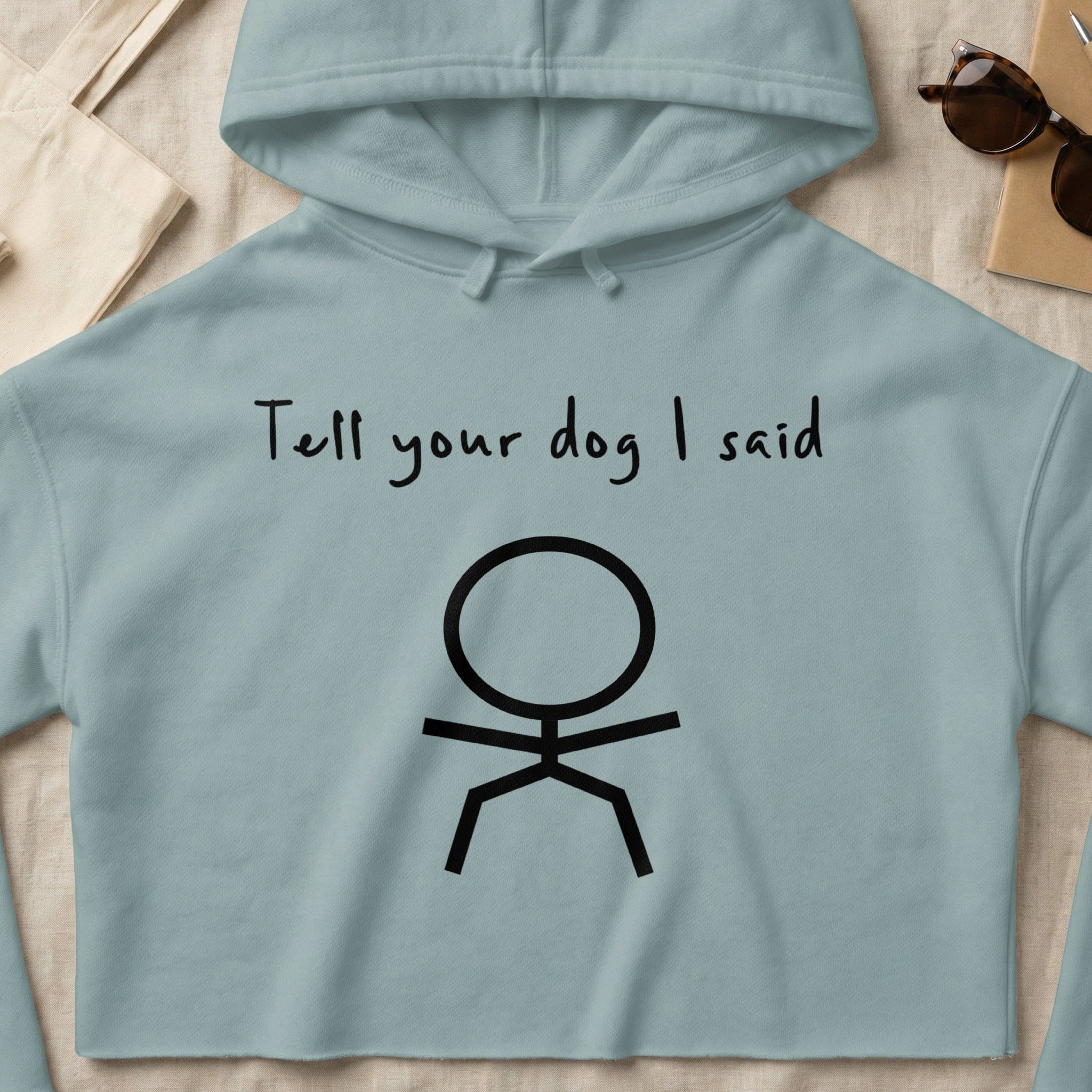Light blue cropped hoodie with "Tell your dog I said" and a stick figure.