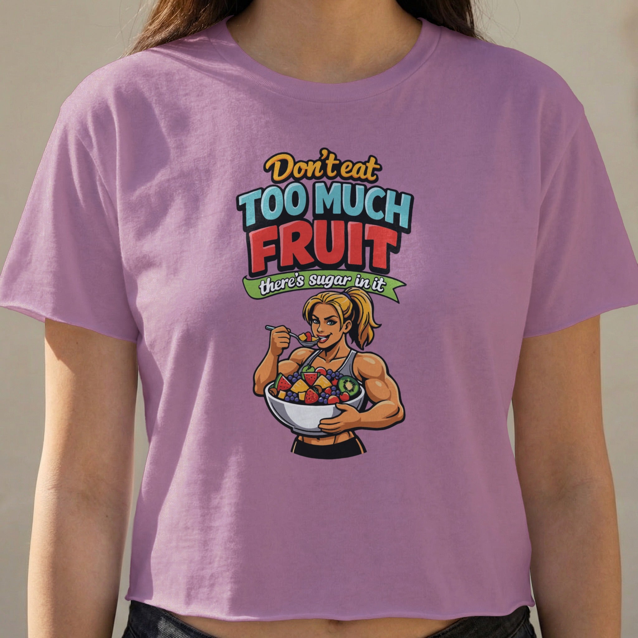 Woman wearing purple t-shirt with cartoon of muscular woman eating fruit.