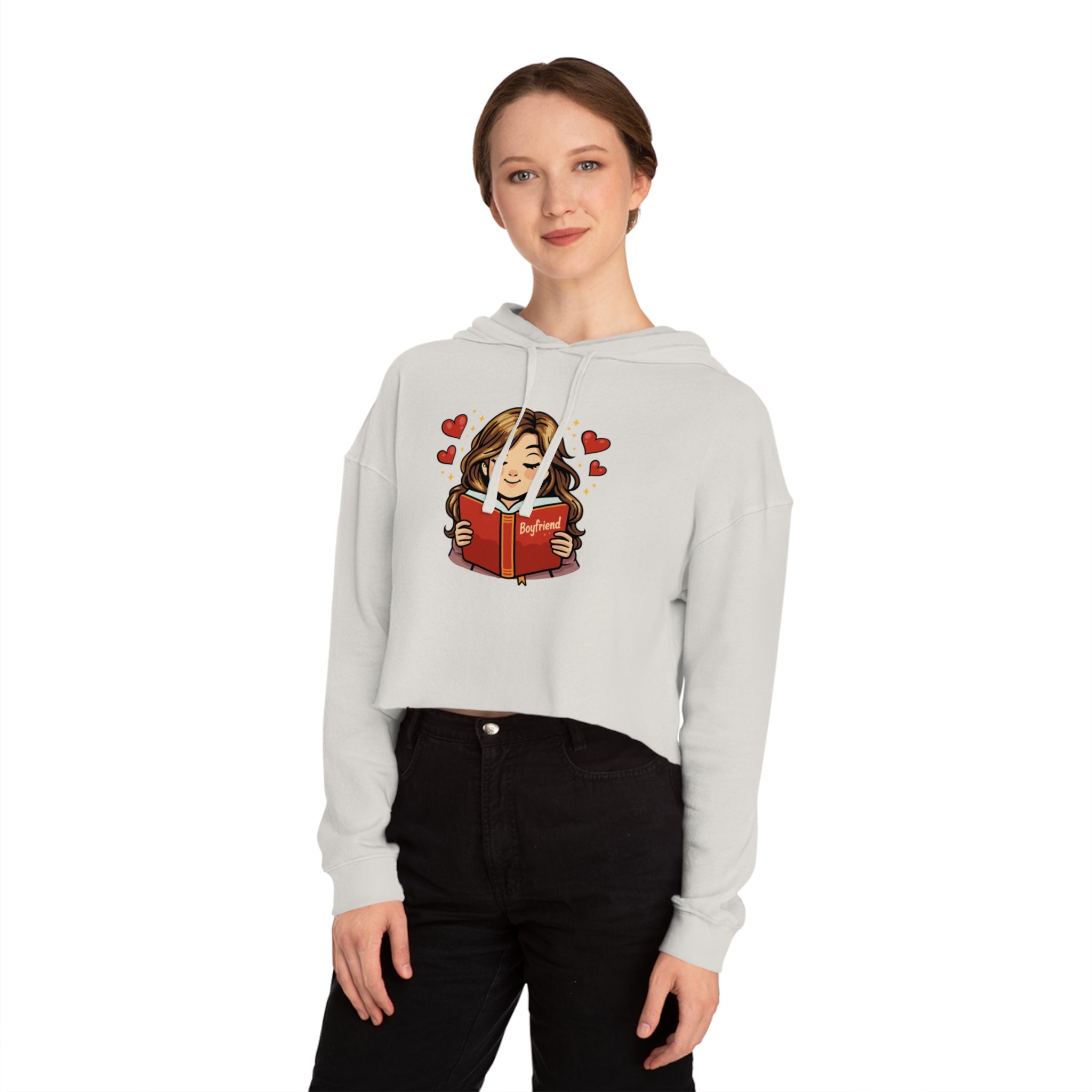 Woman wearing cropped hoodie reads book surrounded by hearts.