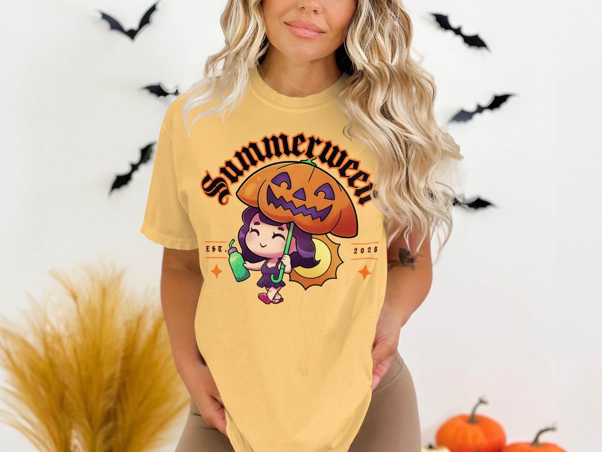 Yellow t-shirt with cartoon girl holding a pumpkin umbrella and text "Summerween Est. 2026".