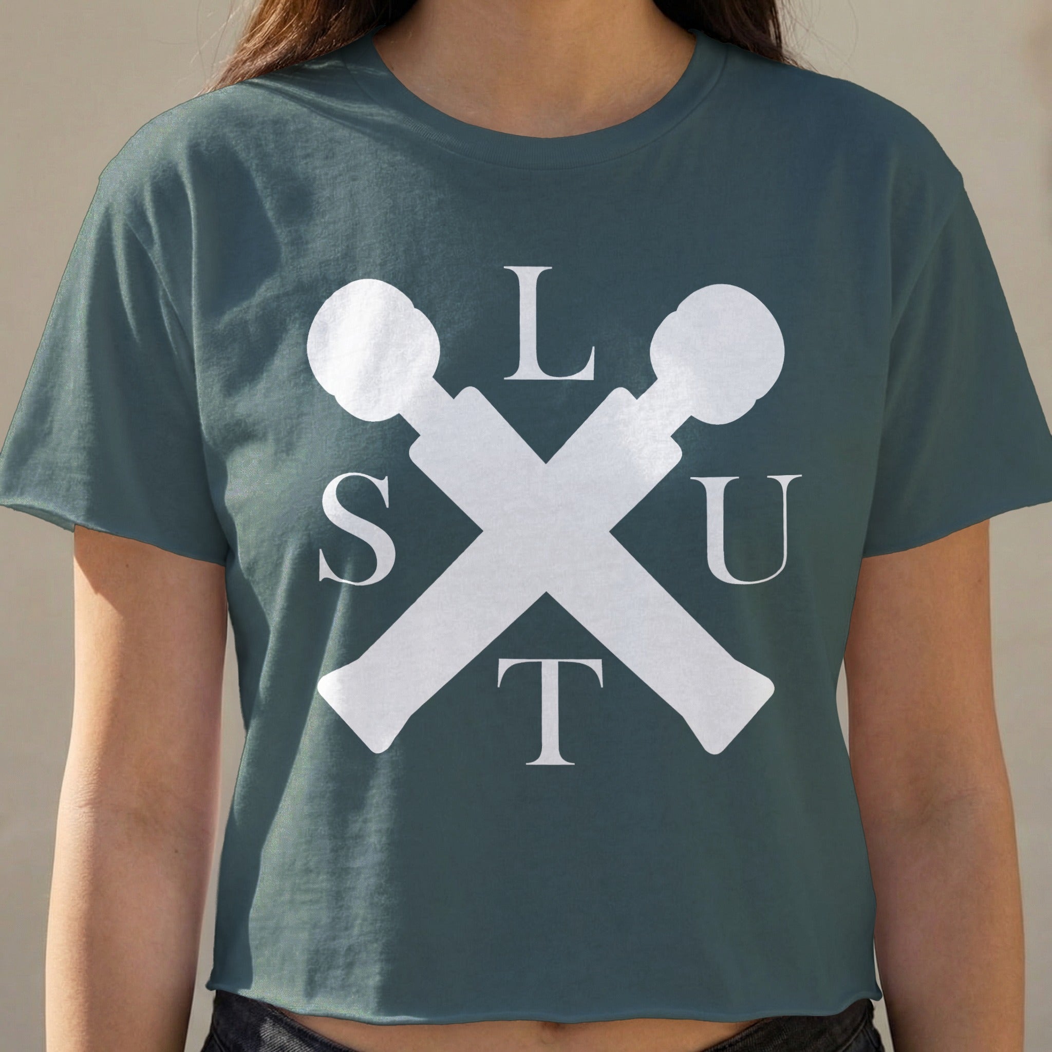 Dark teal cropped t-shirt with white "SLUT" text and crossed microphone icons.