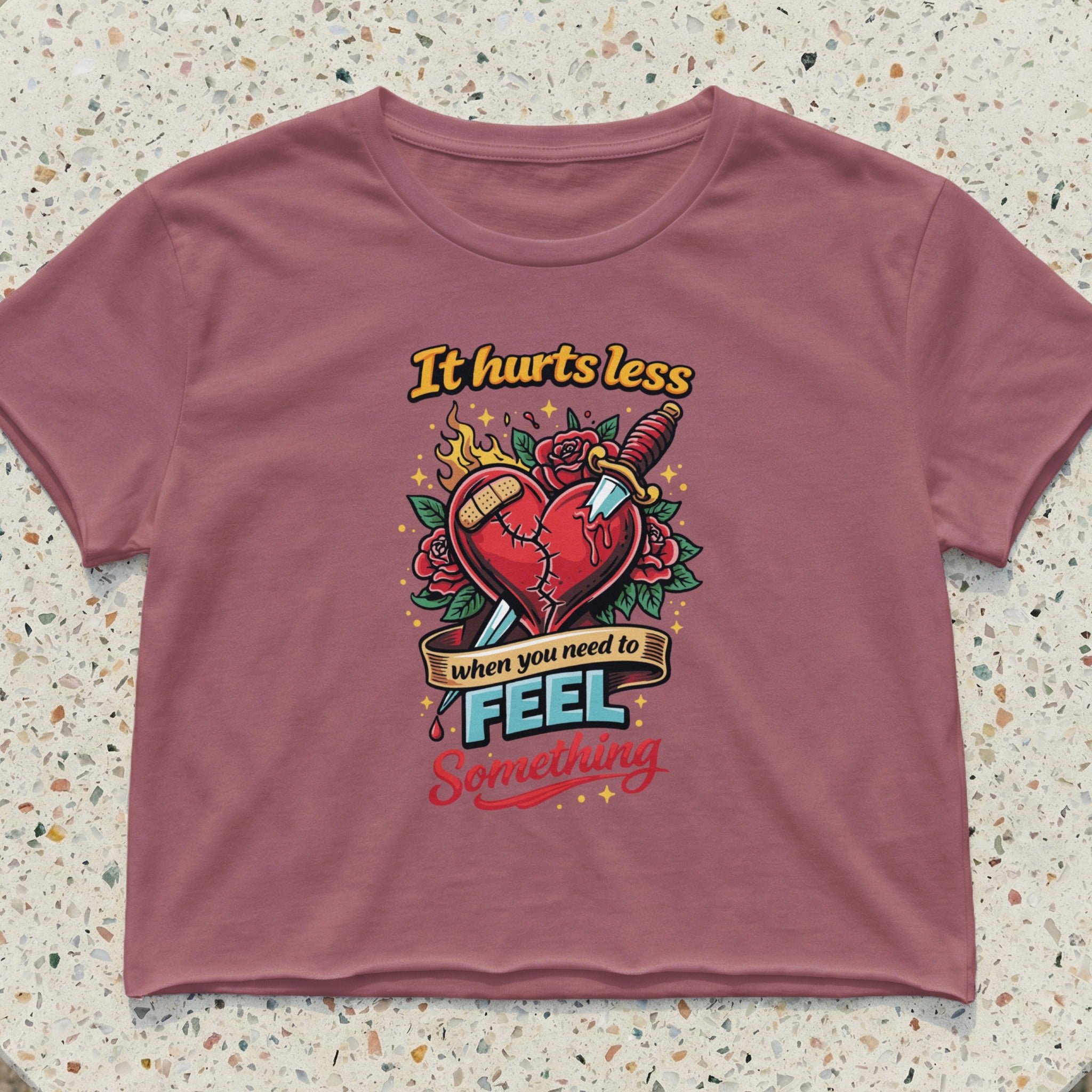 Pink crop top with a graphic of a broken heart, band-aid, knife, and text.