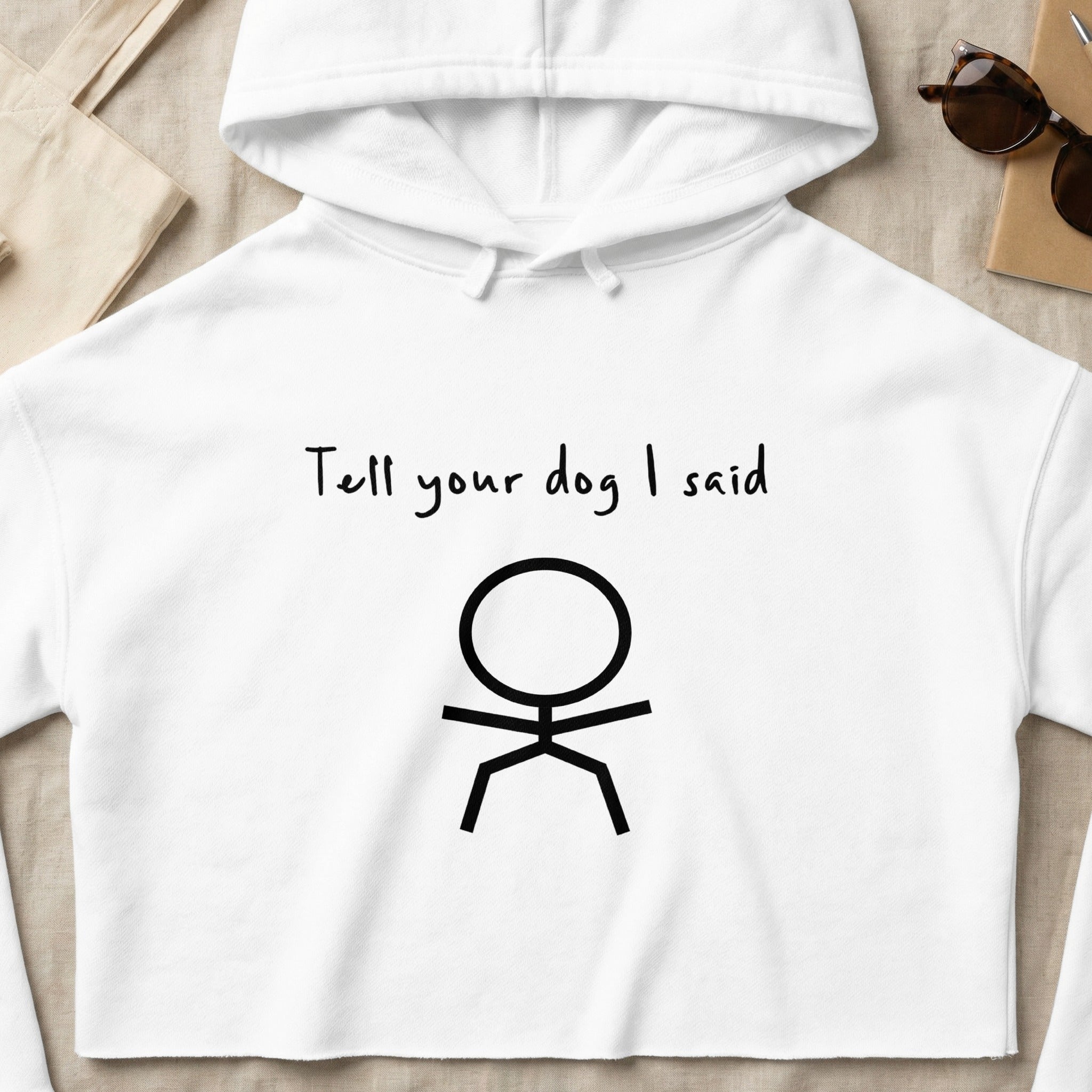 White cropped hoodie with "Tell your dog I said" text and stick figure graphic.