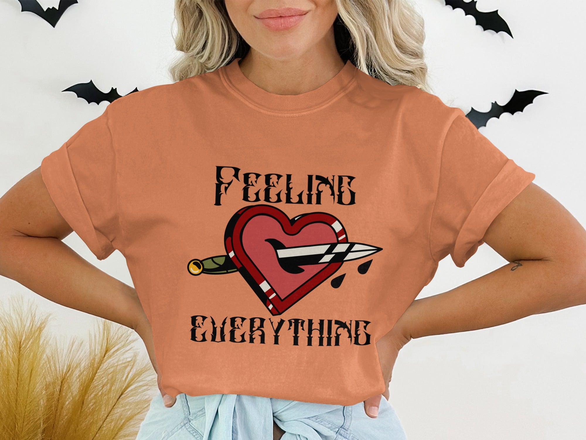 T-shirt with heart pierced by dagger, "Feeling Everything" text.