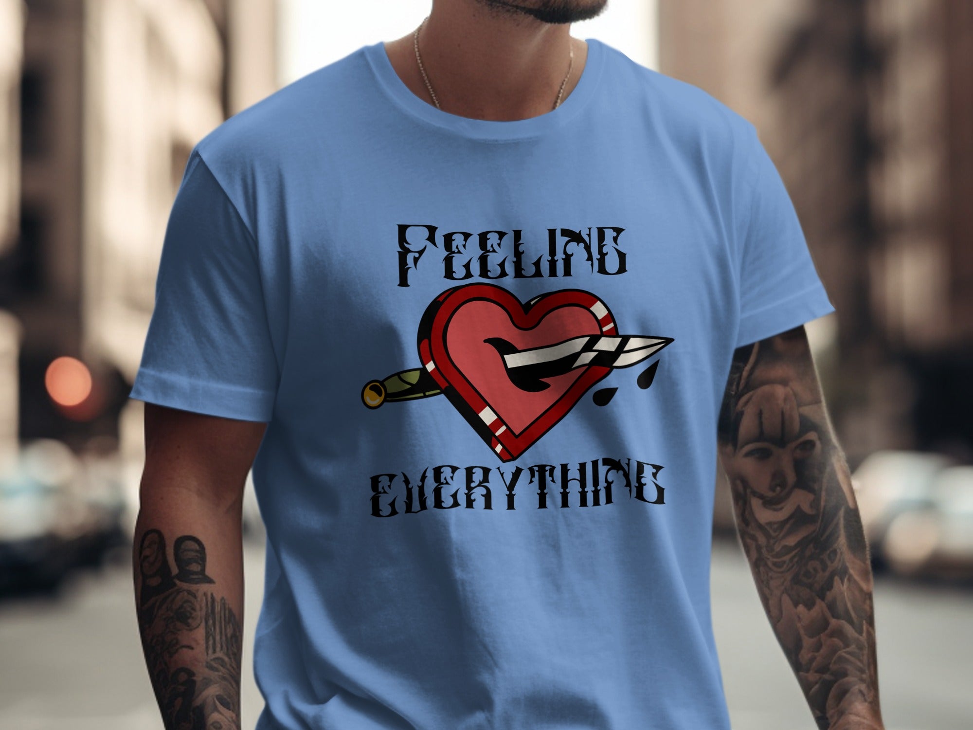 Blue t-shirt with graphic of a broken heart stabbed by a knife, saying "FEELING EVERYTHING".
