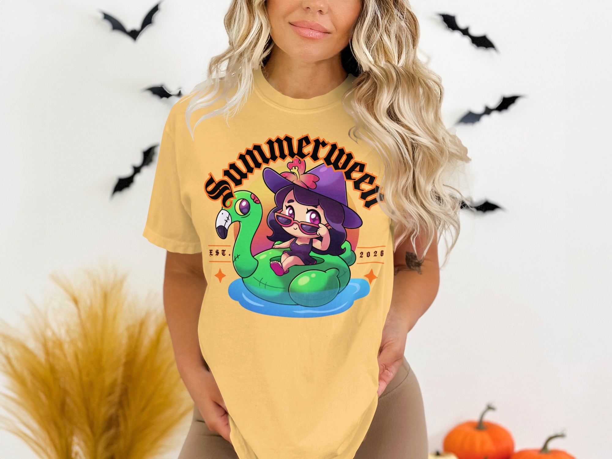 Yellow t-shirt with a cartoon witch on a flamingo float, "Summerween Est. 2026" text.