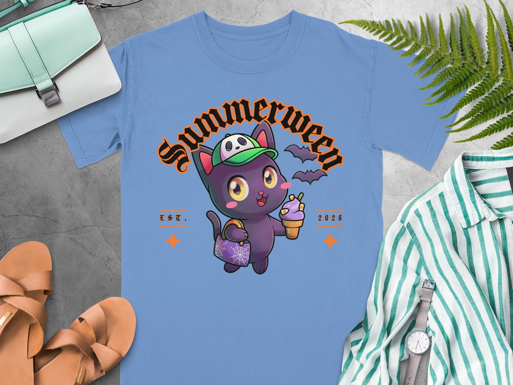 Light blue t-shirt with a cartoon black cat wearing a green hat and holding ice cream.