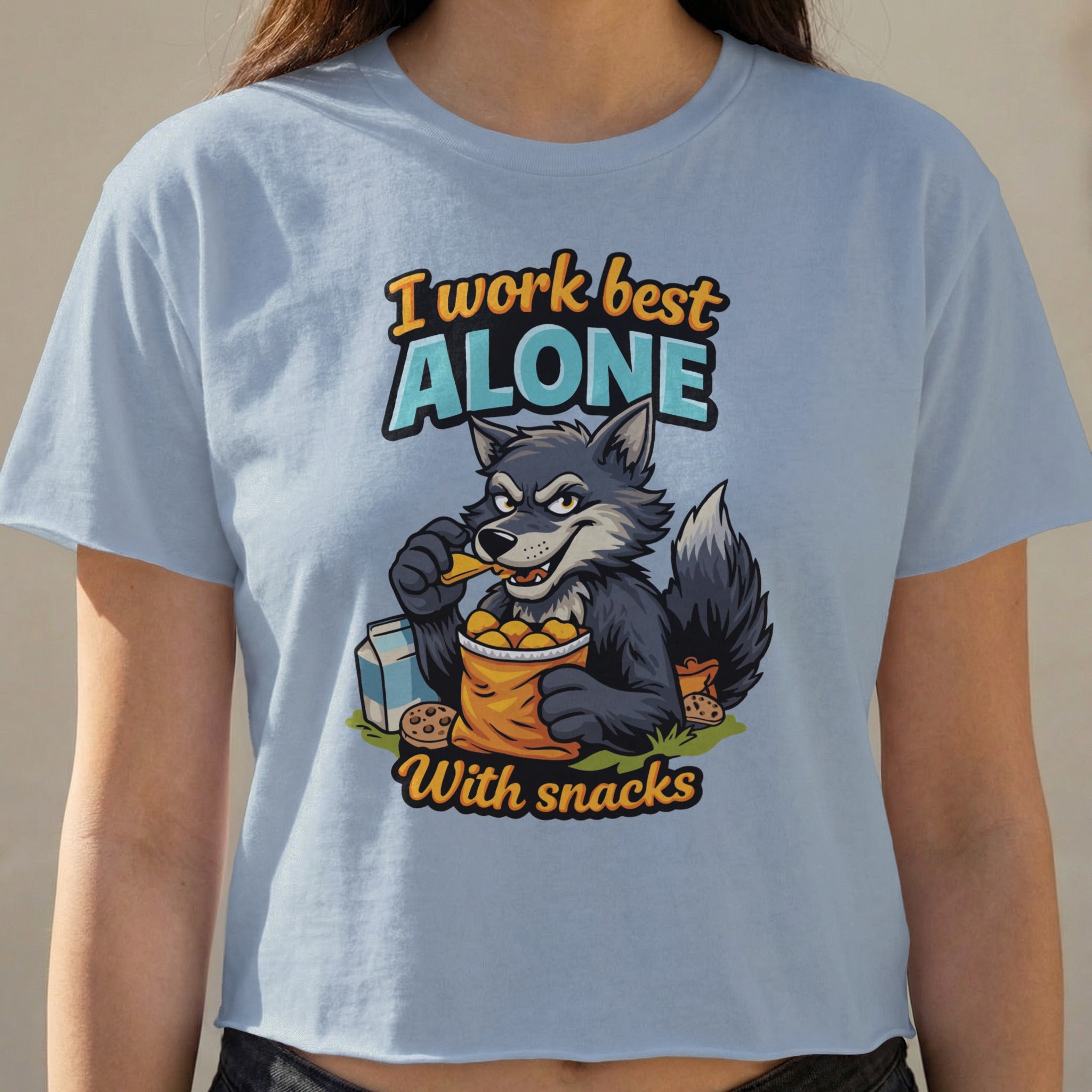 Gray wolf character in t-shirt artwork eating chips with text "I work best alone with snacks".