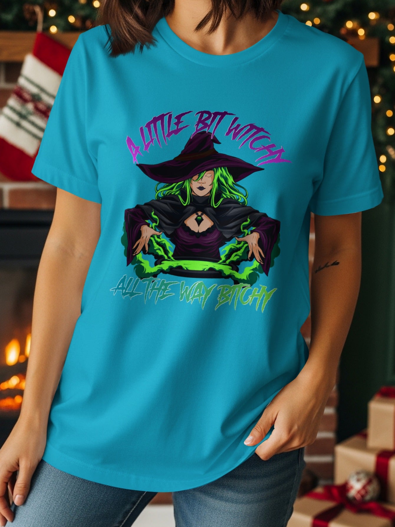 Turquoise t-shirt with graphic of a witch and text "A Little Bit Witchy All The Way Bitchy".