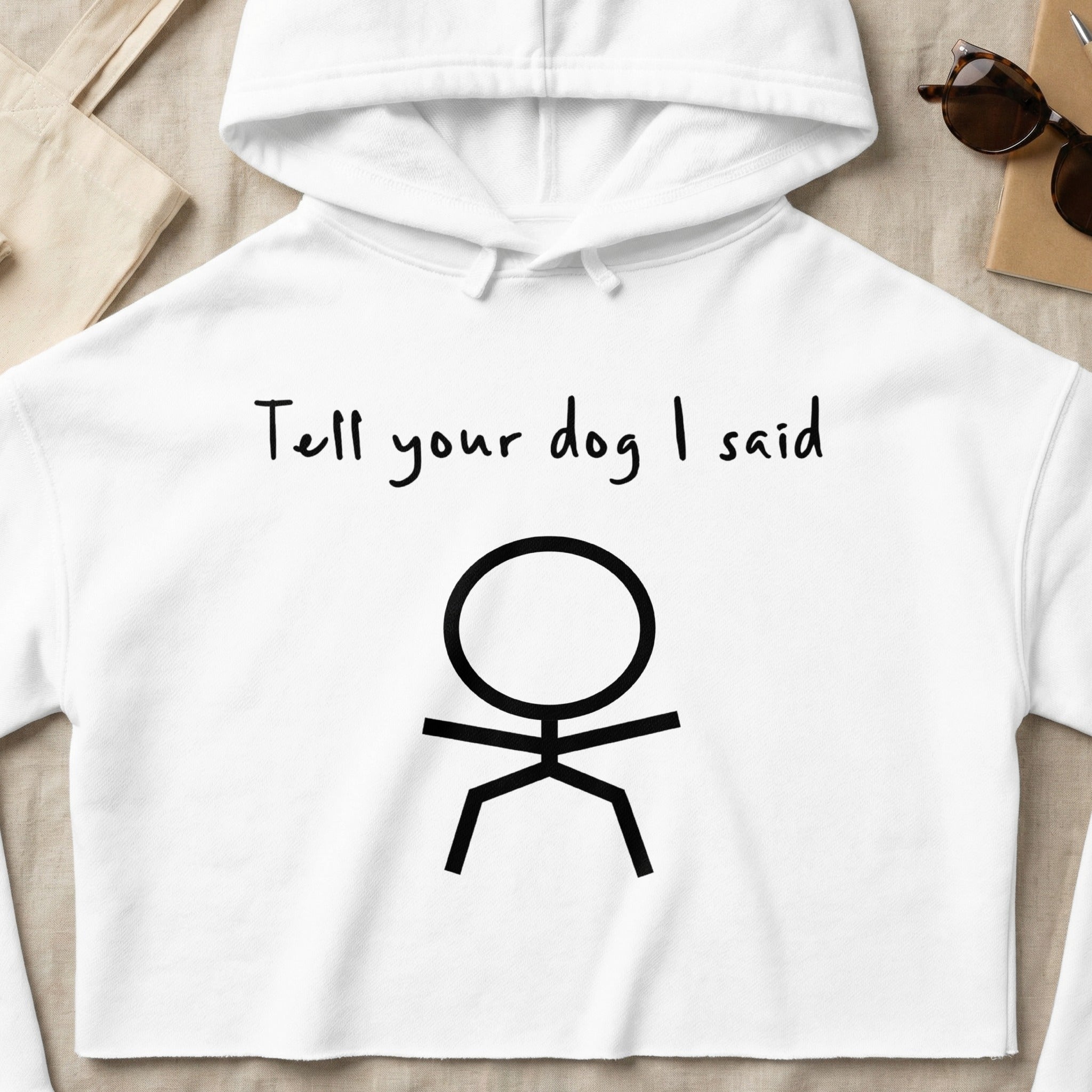 White cropped hoodie with "Tell your dog I said" and a stick figure.