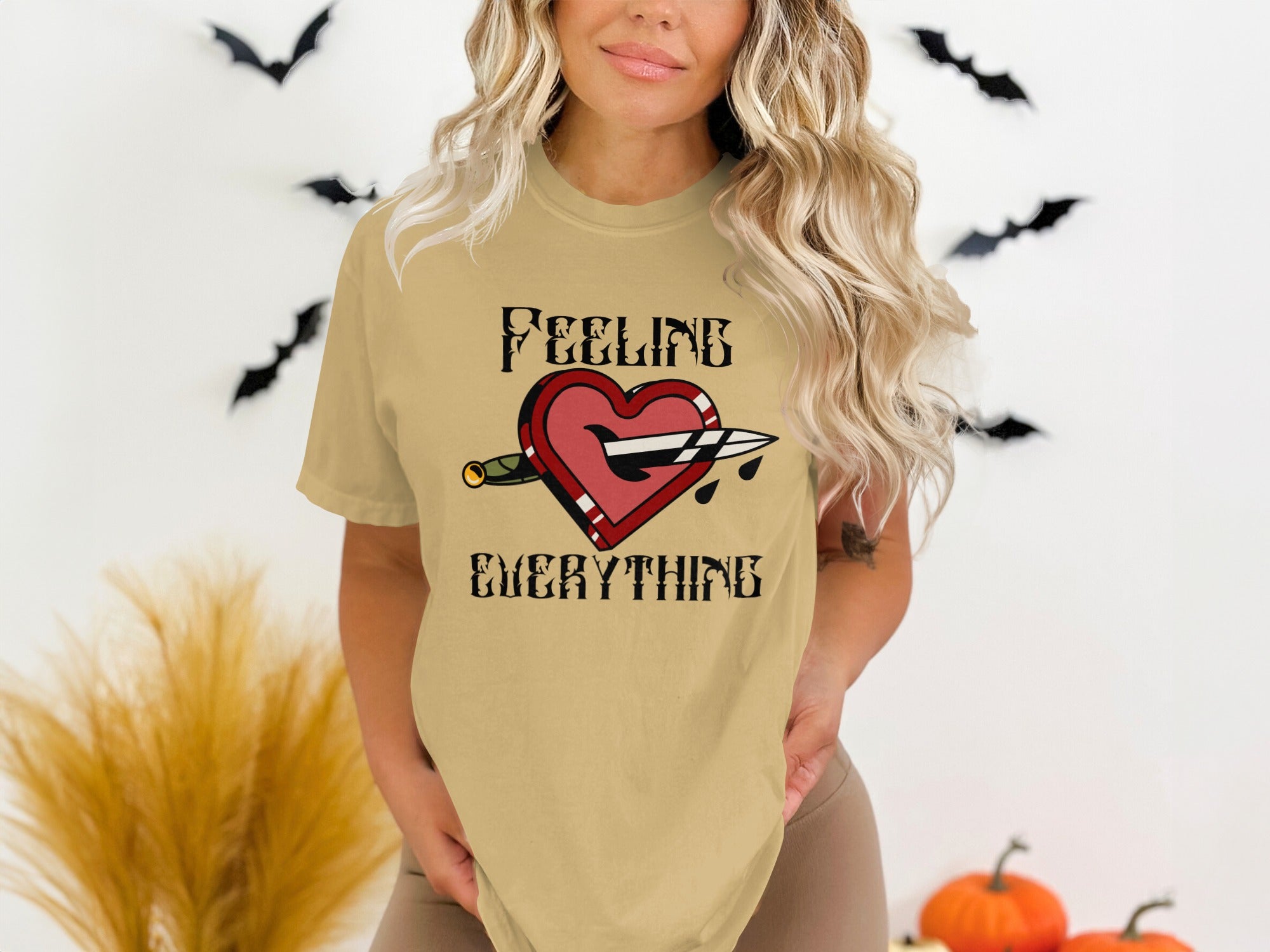 T-shirt graphic of a heart pierced by a dagger with blood drops and text "FEELING EVERYTHING".