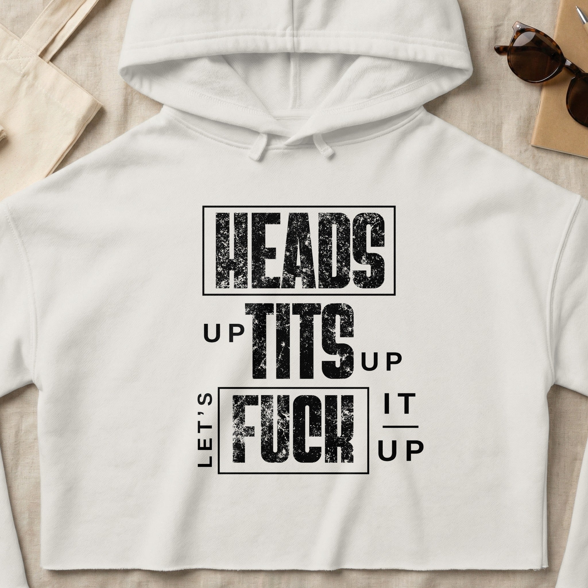 White cropped hoodie with bold black text reading "HEADS UP TITS UP LET'S FUCK UP".