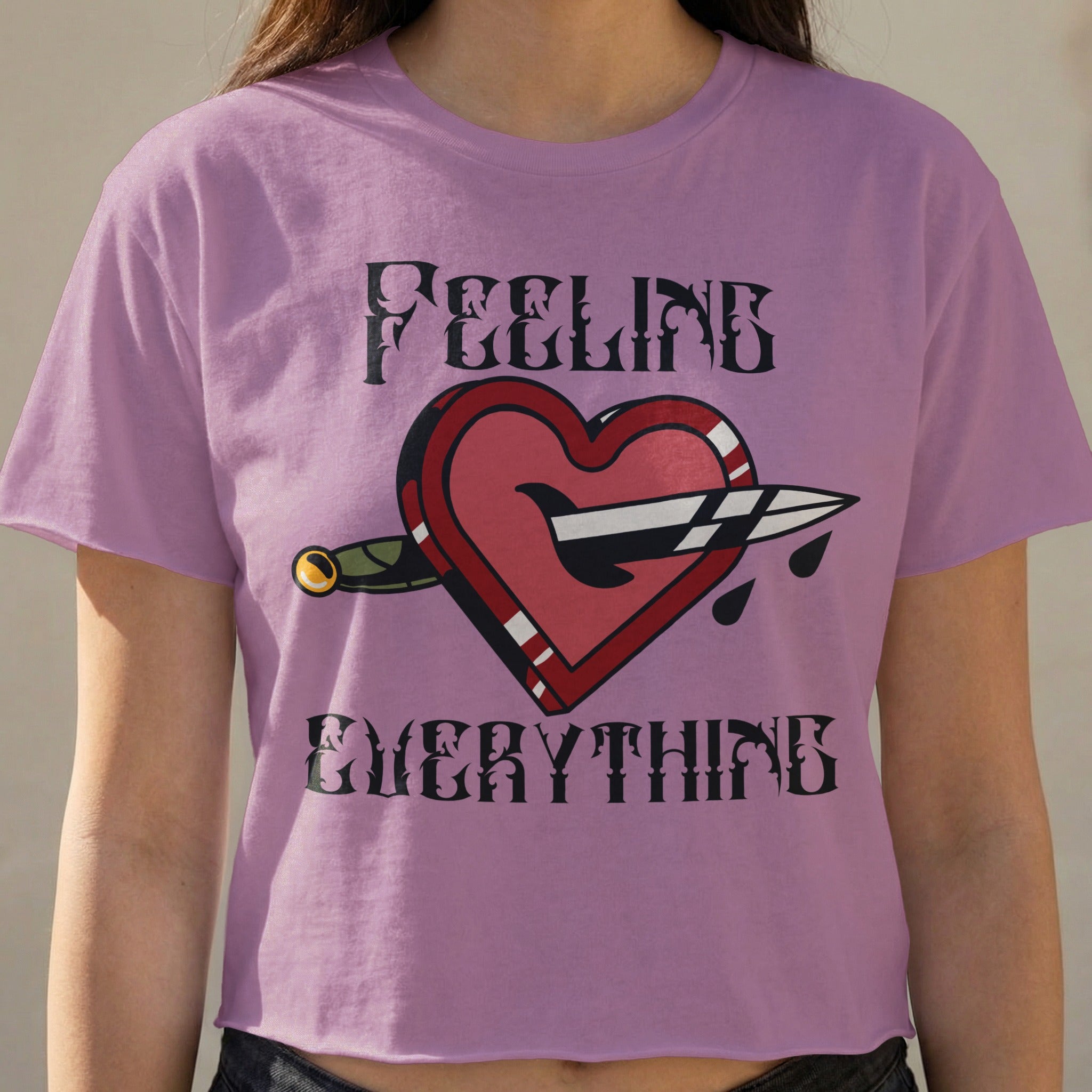 Purple t-shirt with a heart pierced by a dagger, reading "FEELING EVERYTHING".