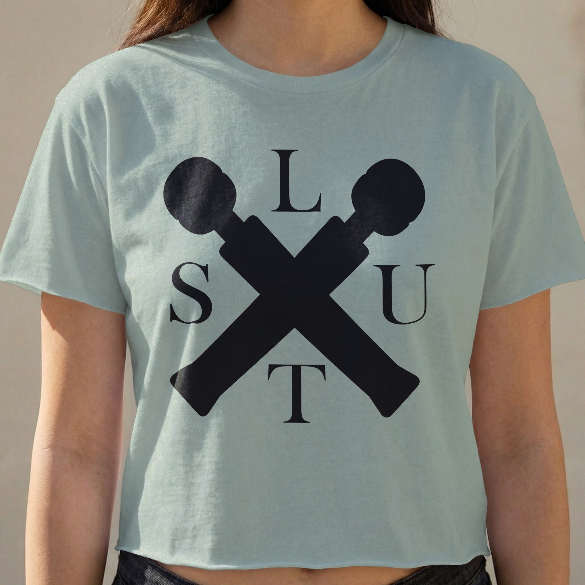 Light blue t-shirt with "SLUT" in black block letters and crossed microphones.