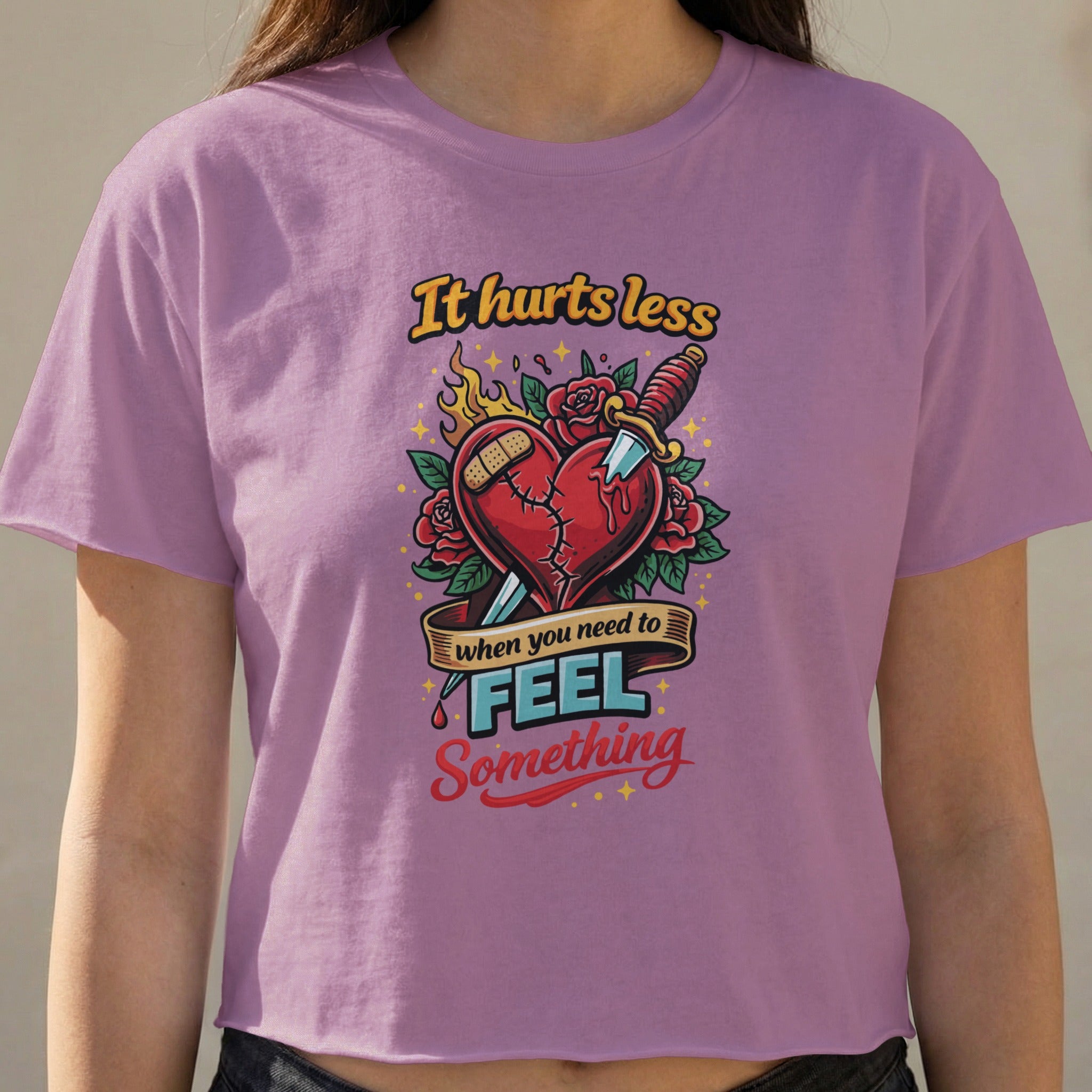 Purple crop top with heart and knife graphic that says "It hurts less when you need to feel something".