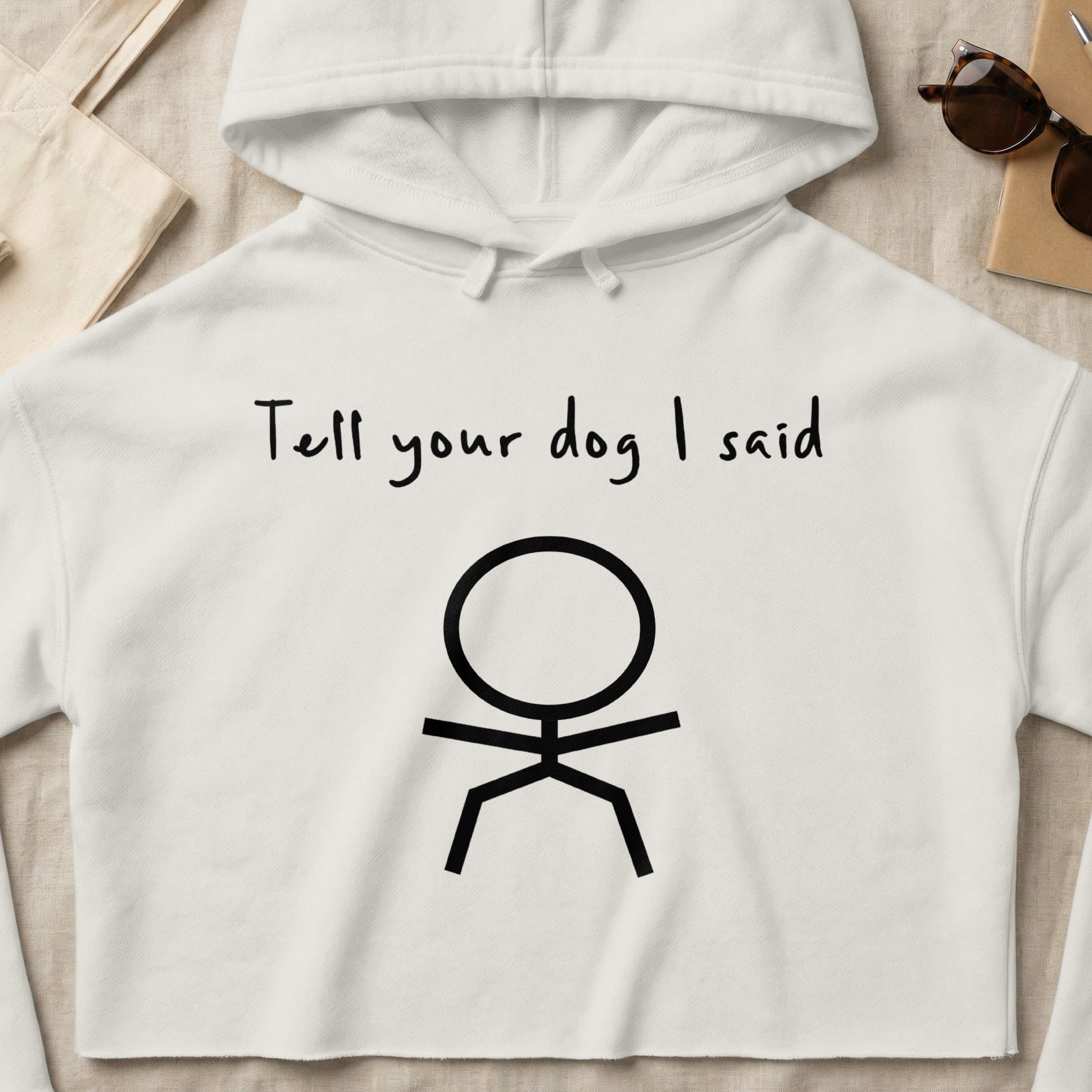 White cropped hoodie with "Tell your dog I said" and stick figure graphic.
