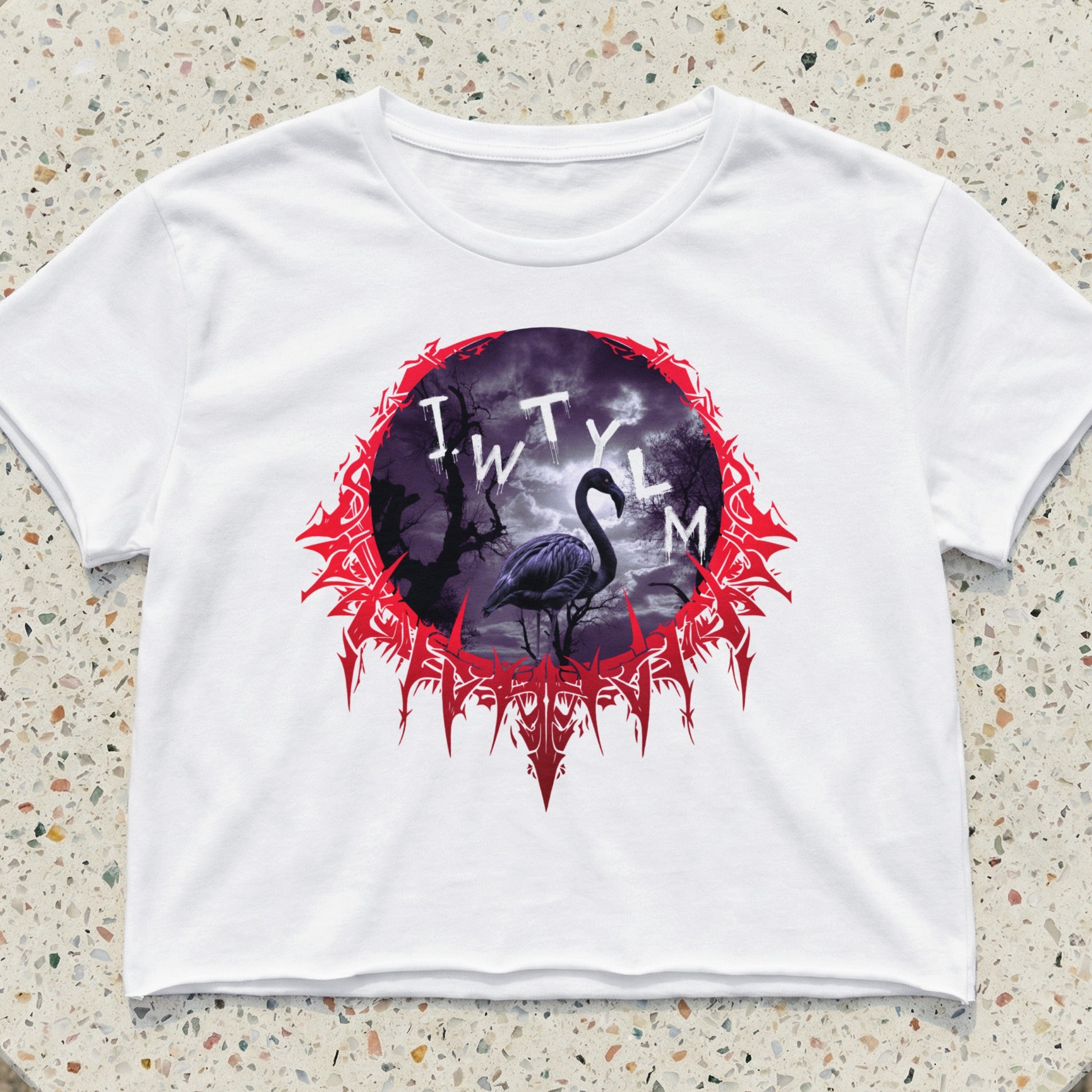 White crop top featuring a circular graphic of a flamingo in a dark, spooky forest.