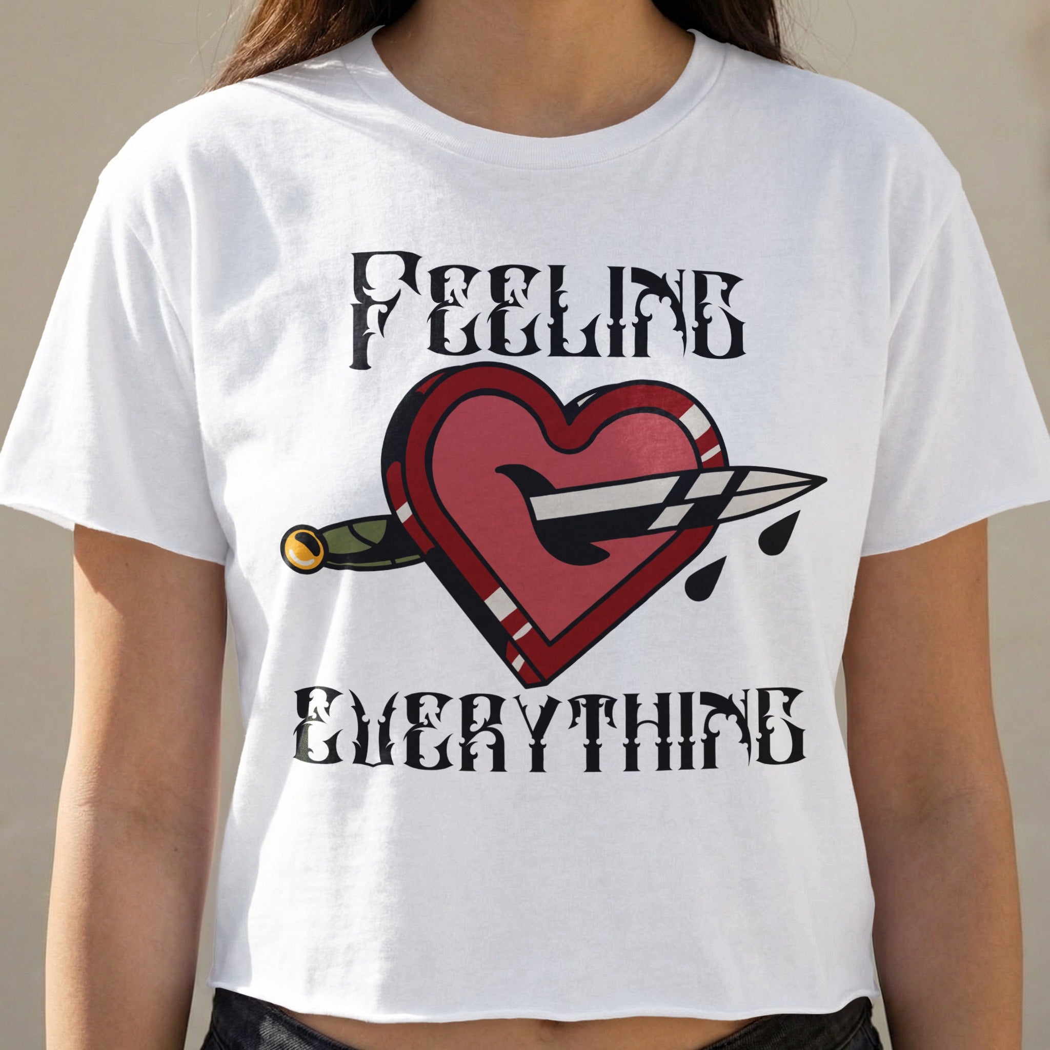 White t-shirt with dagger piercing heart graphic and text "FEELING EVERYTHING".