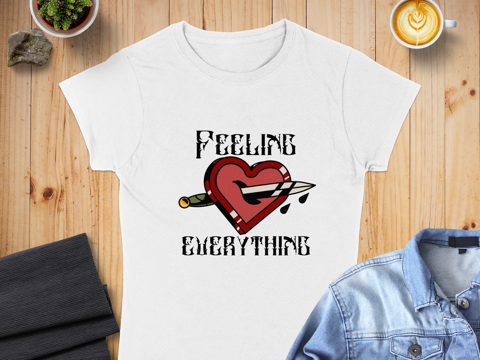 White t-shirt with "FEELING EVERYTHING" text and a heart pierced by a dagger.