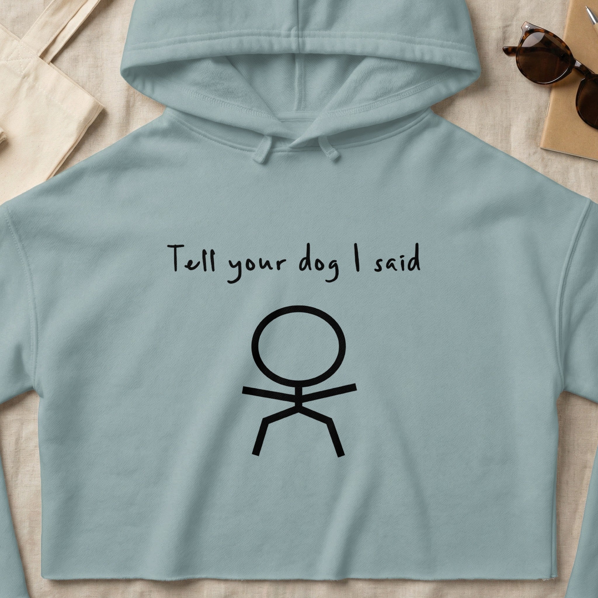Light blue cropped hoodie with "Tell your dog I said" text and stick figure.