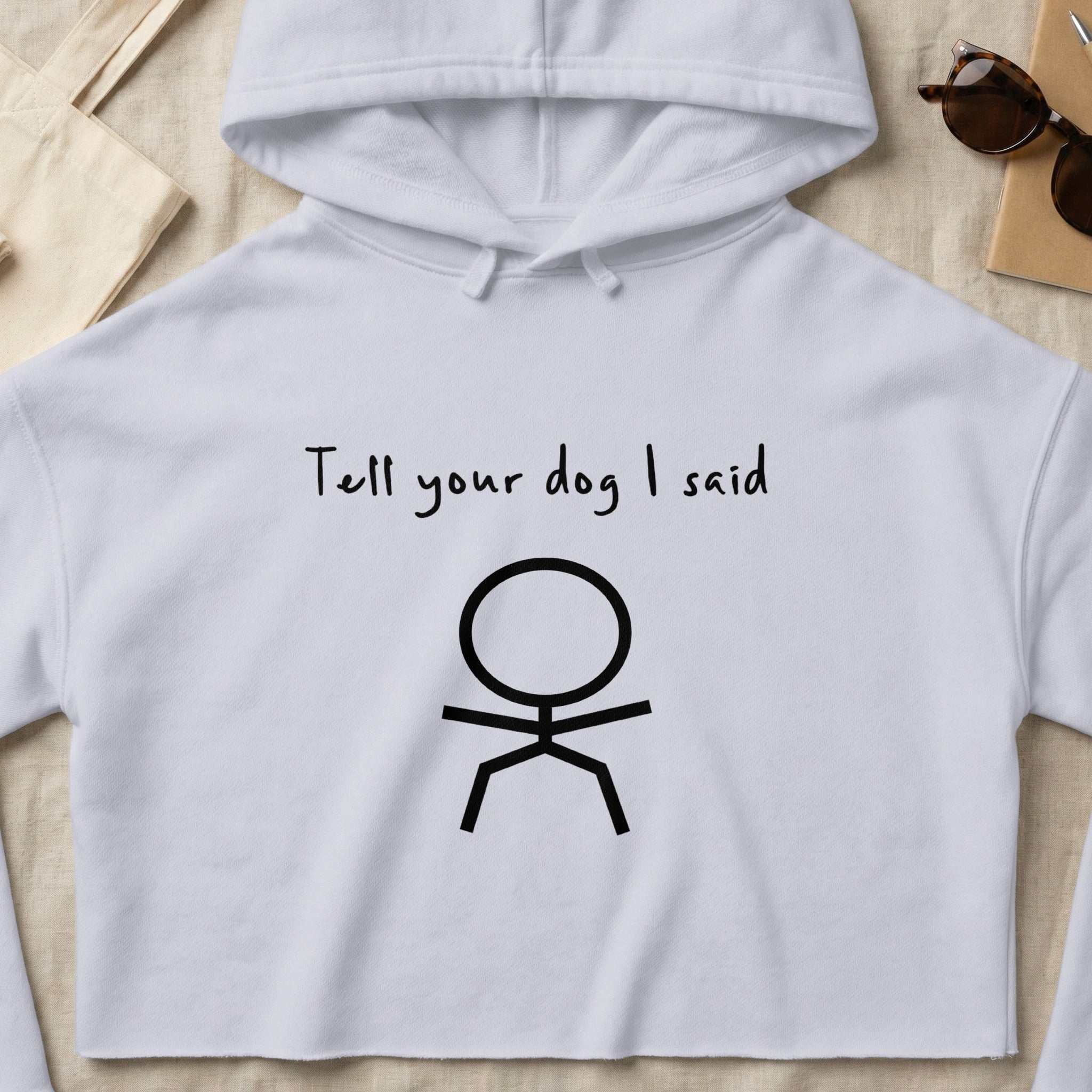 White cropped hoodie with "Tell your dog I said" and a stick figure.
