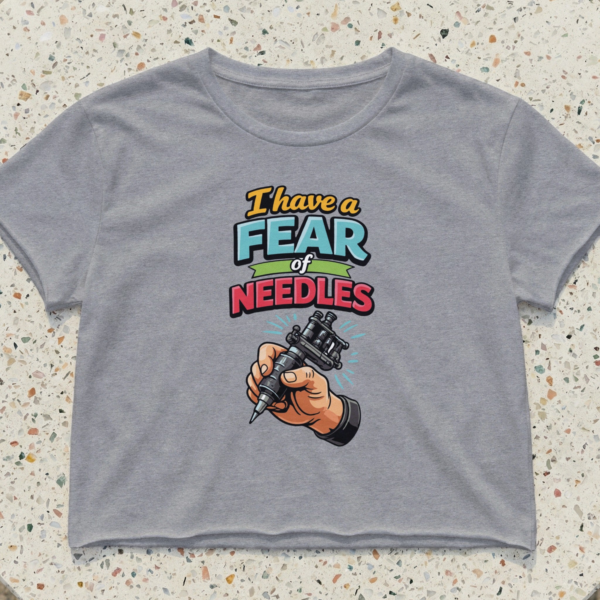 Gray cropped t-shirt with "I have a fear of NEEDLES" and a tattoo gun illustration.