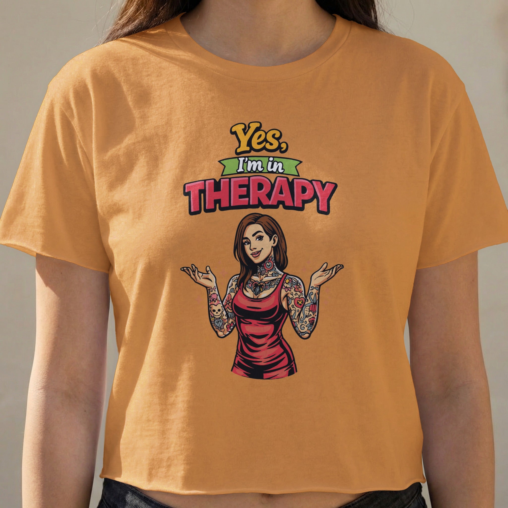 Orange crop top with "Yes, I'm in Therapy" text and tattooed woman graphic.