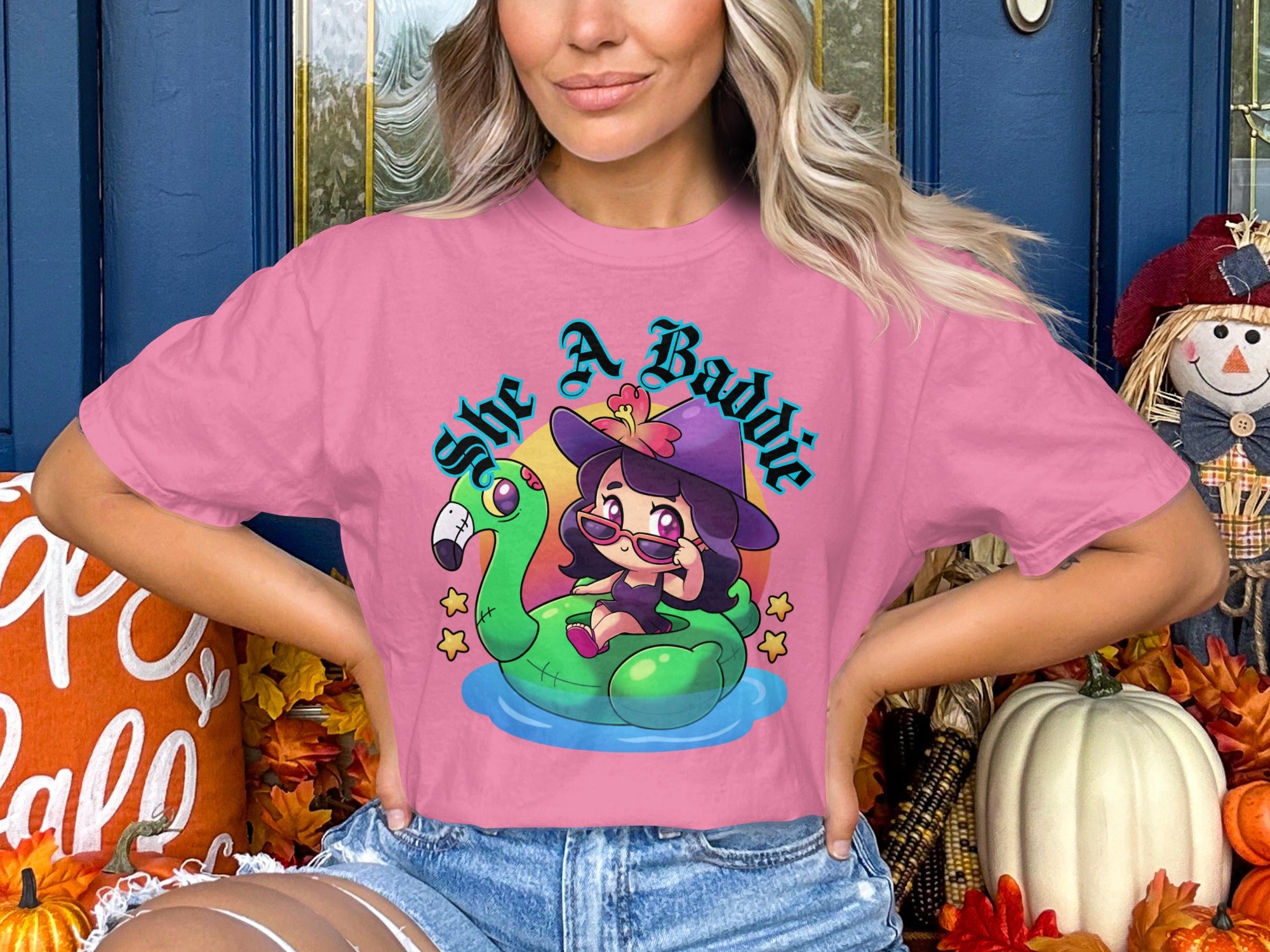 Pink t-shirt with cartoon witch on flamingo float and text "she A Baddie".