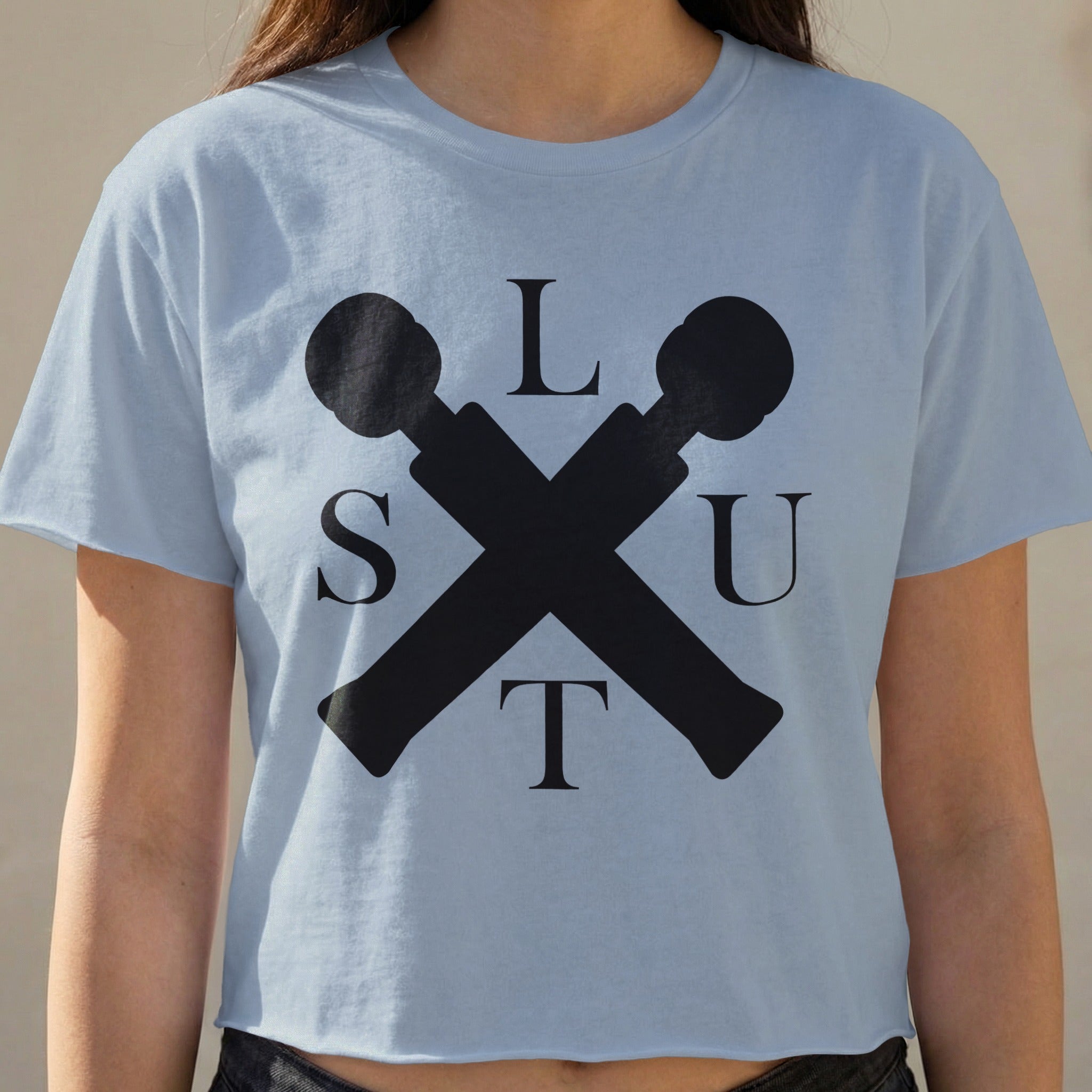 Light blue cropped t-shirt with black crossed microphone graphic and the letters L, S, U, T.