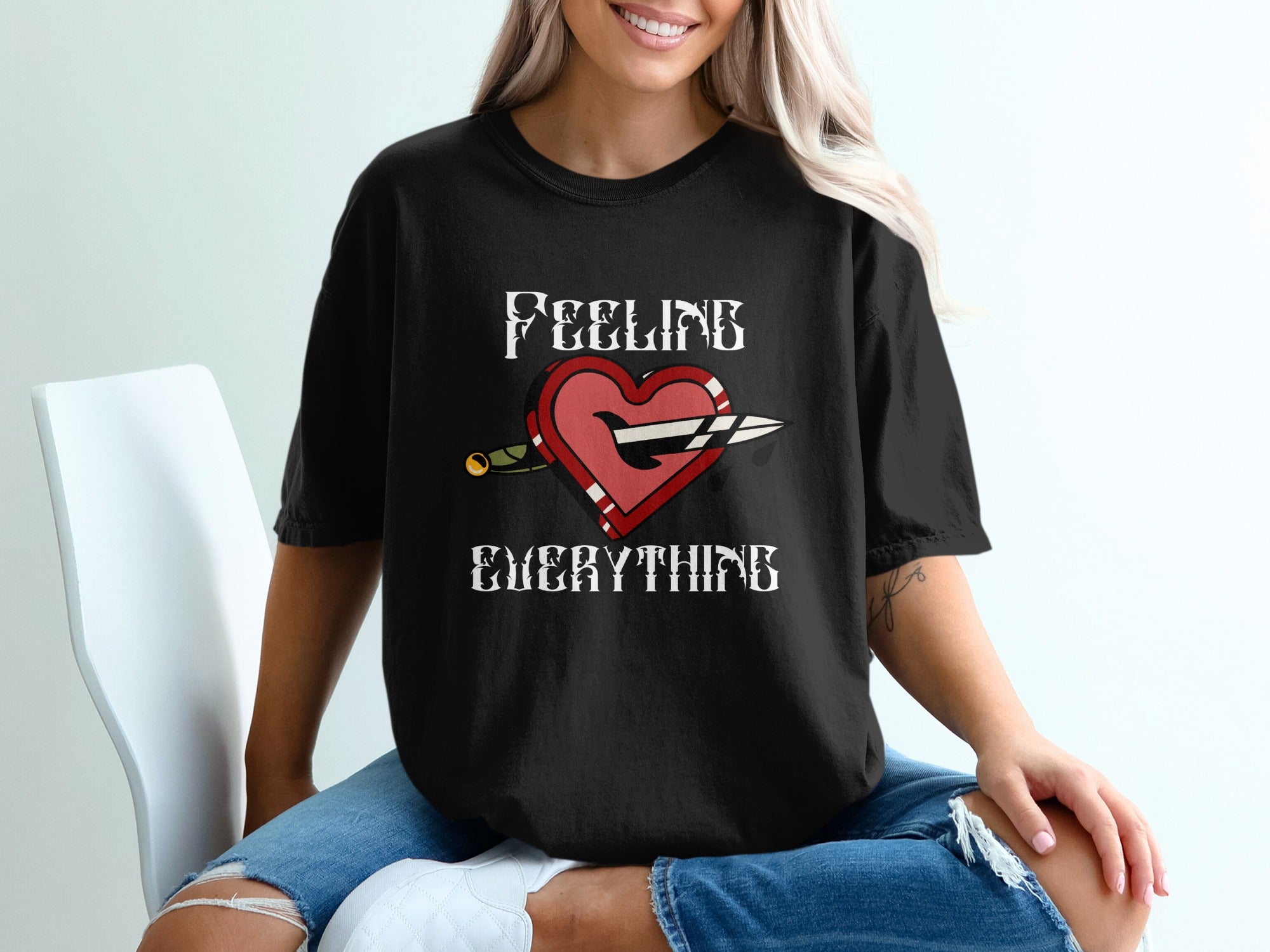 Black t-shirt with a heart pierced by a dagger and the words "FEELING EVERYTHING".