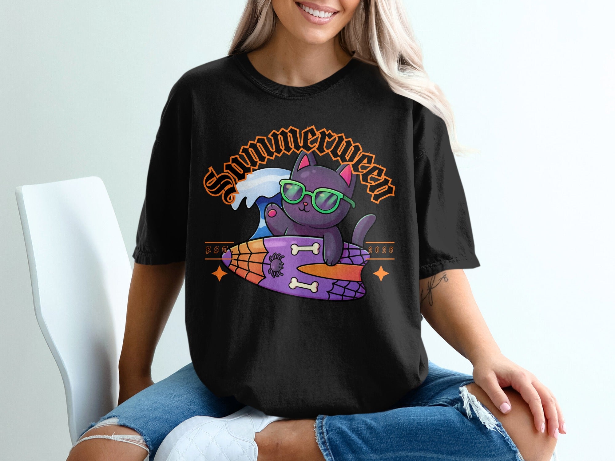 Black t-shirt with a graphic of a cat wearing sunglasses on a surfboard with "Summerween" text.