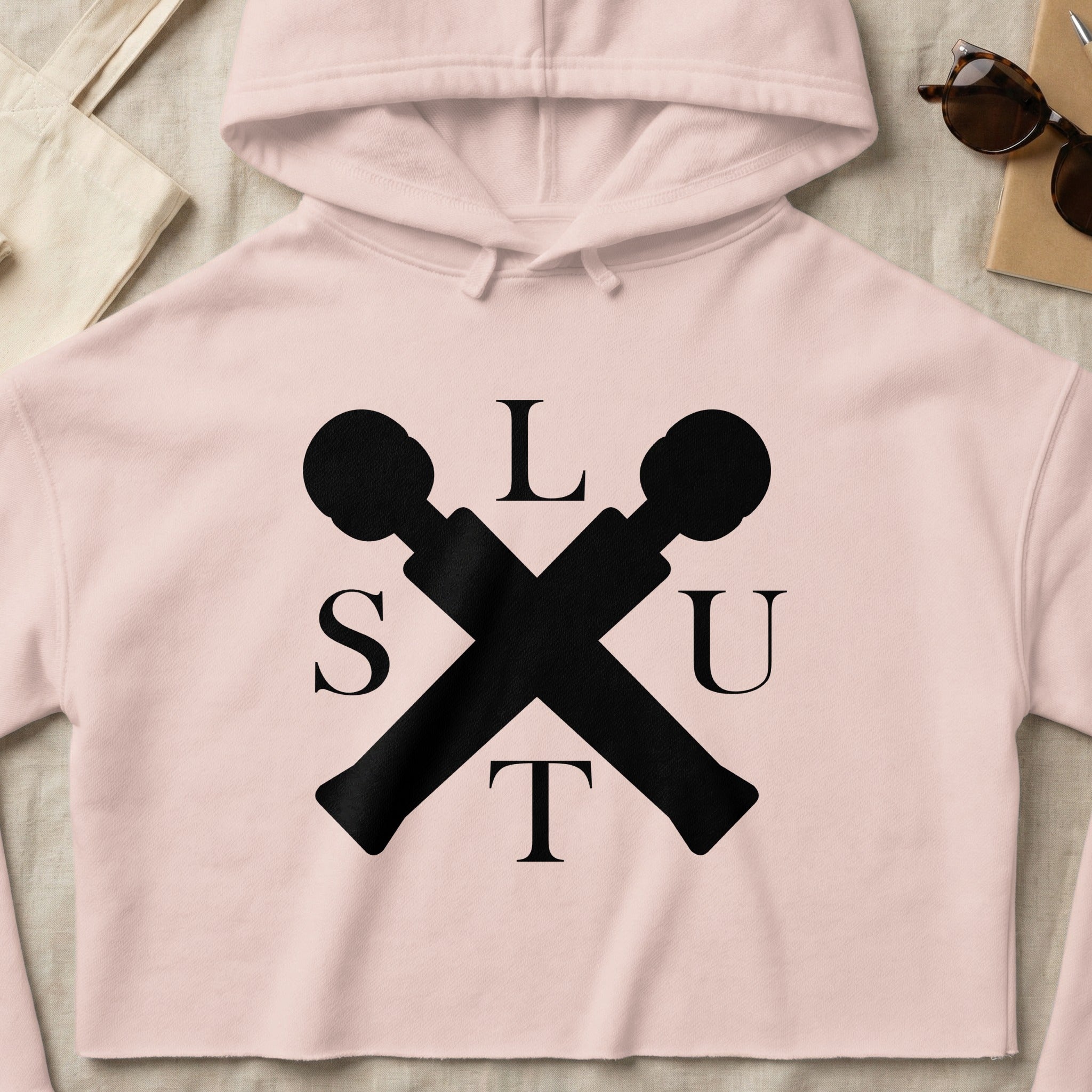 Black crossed microphones with "SLUT" text on light pink crop hoodie.