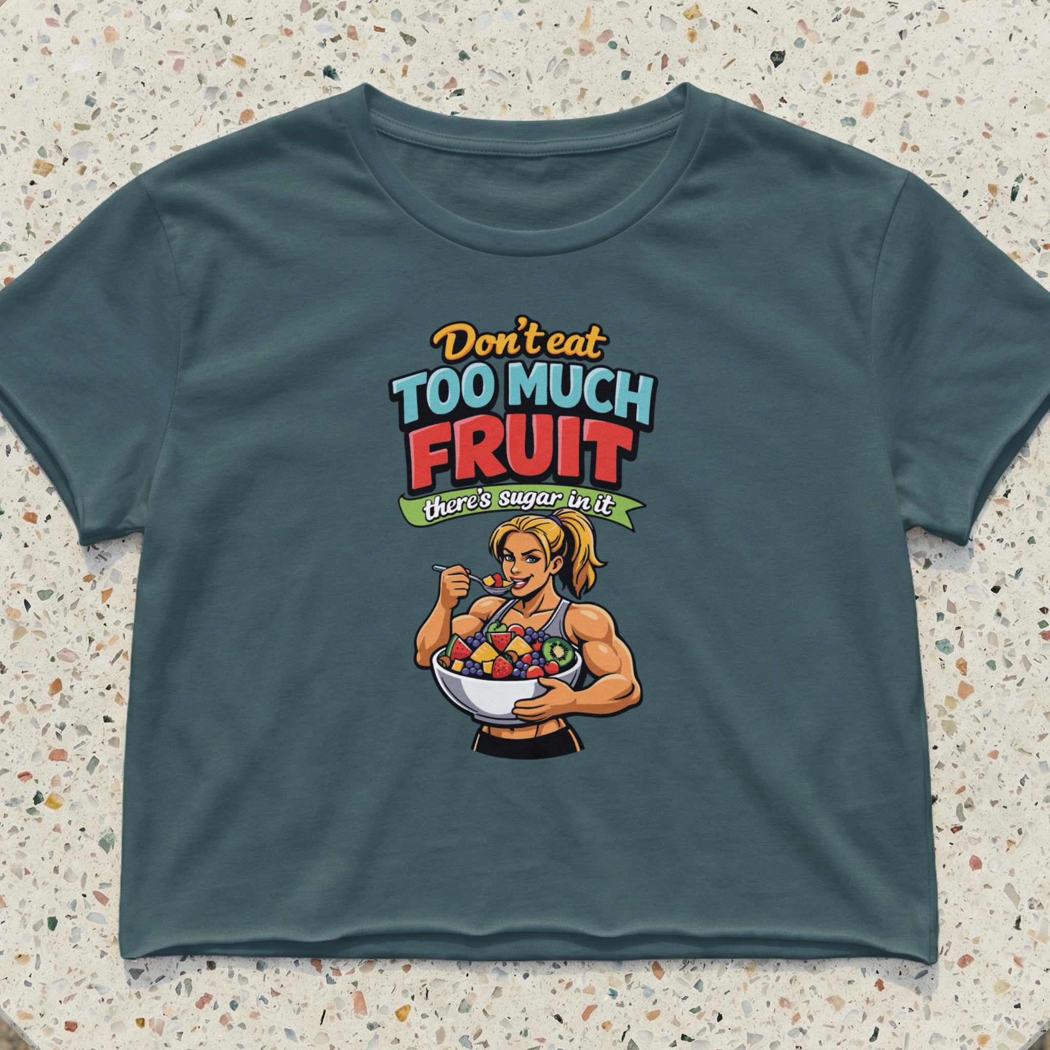 Cropped t-shirt with graphic of muscular woman eating from a fruit bowl.
